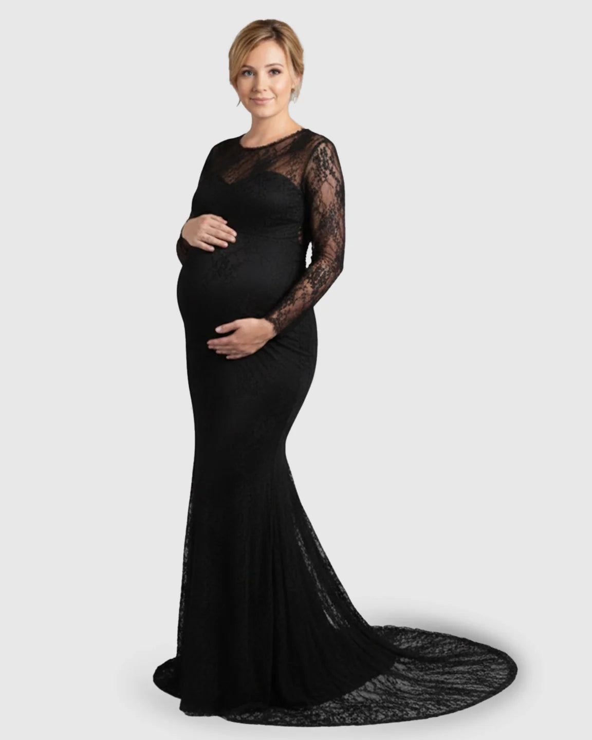 Pregnant woman in a black sheer lace trumpet maternity gown with long sleeves and a mermaid-style skirt.