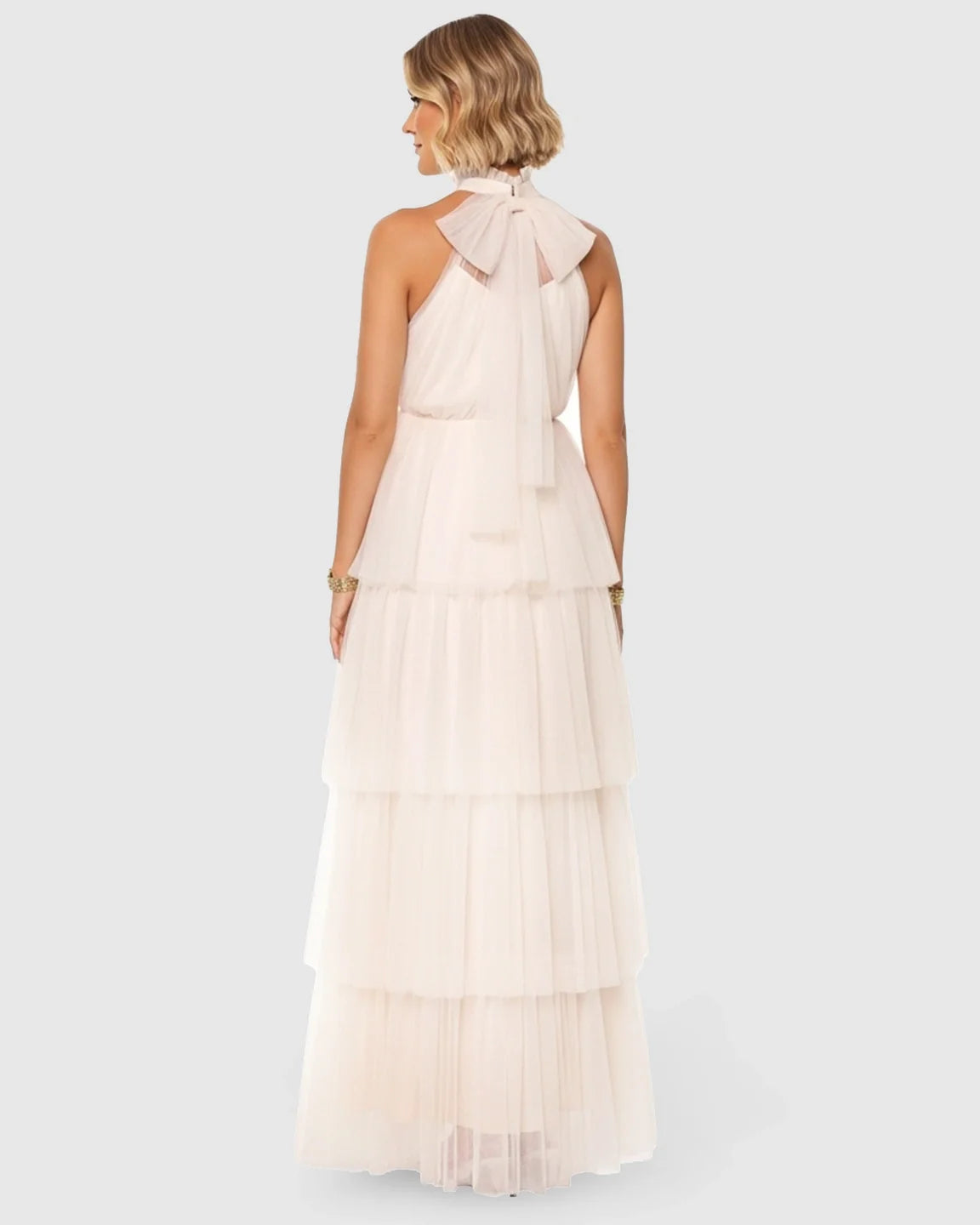 Halter neck tiered mesh maternity gown in light pink, featuring a large bow detail at the back.