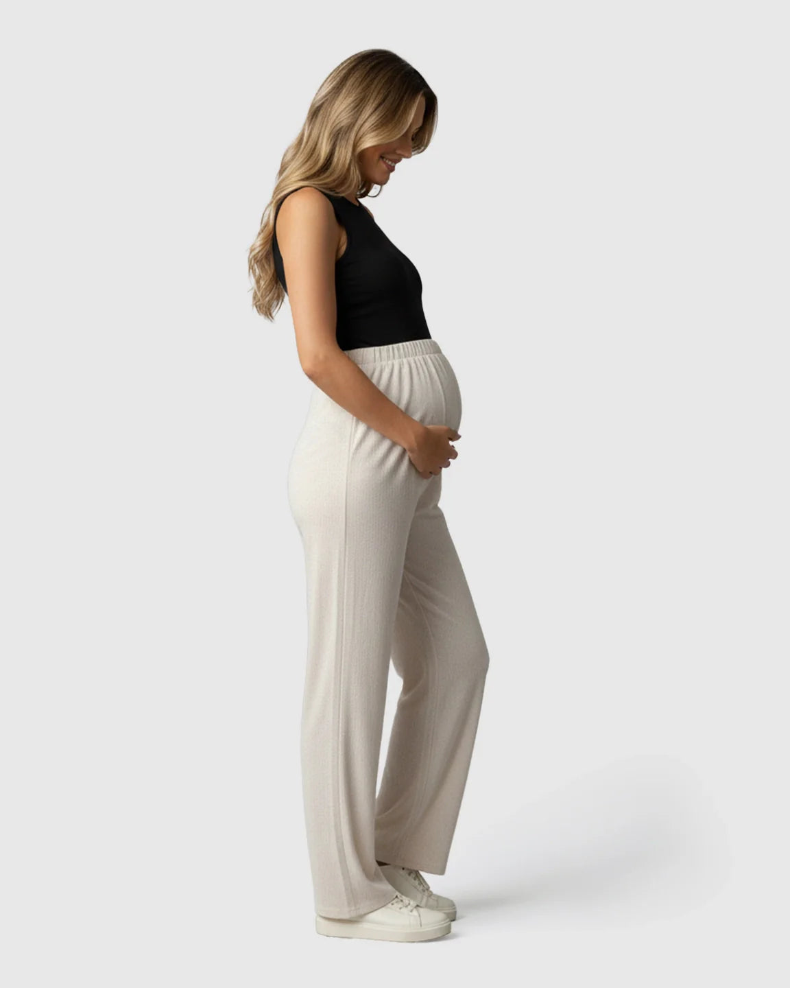 Pregnant woman in light beige wide-leg maternity pants with an elastic over-belly fit, paired with a black tank top.