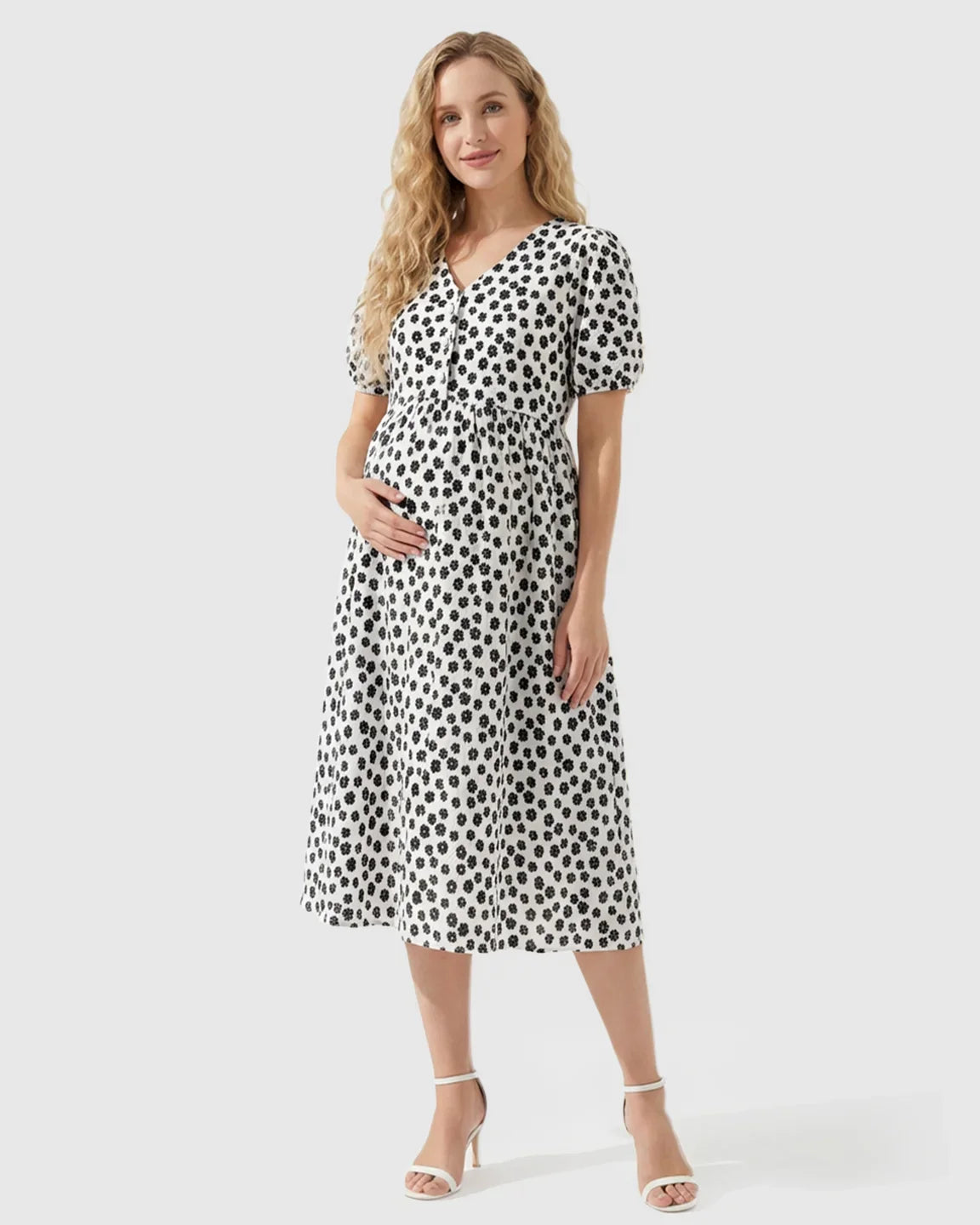 Smiling pregnant woman in a white midi nursing dress with black floral print, V-neck, and button-front.
