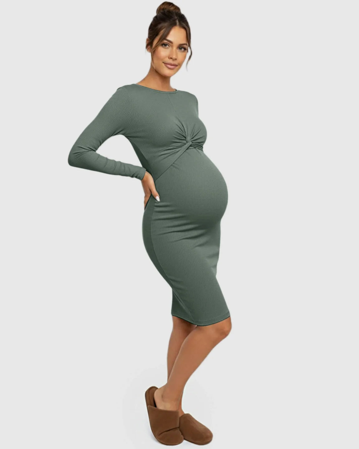 Pregnant woman in a sage green ribbed bodycon maternity dress with a twist-front detail, long sleeves, and empire waist.