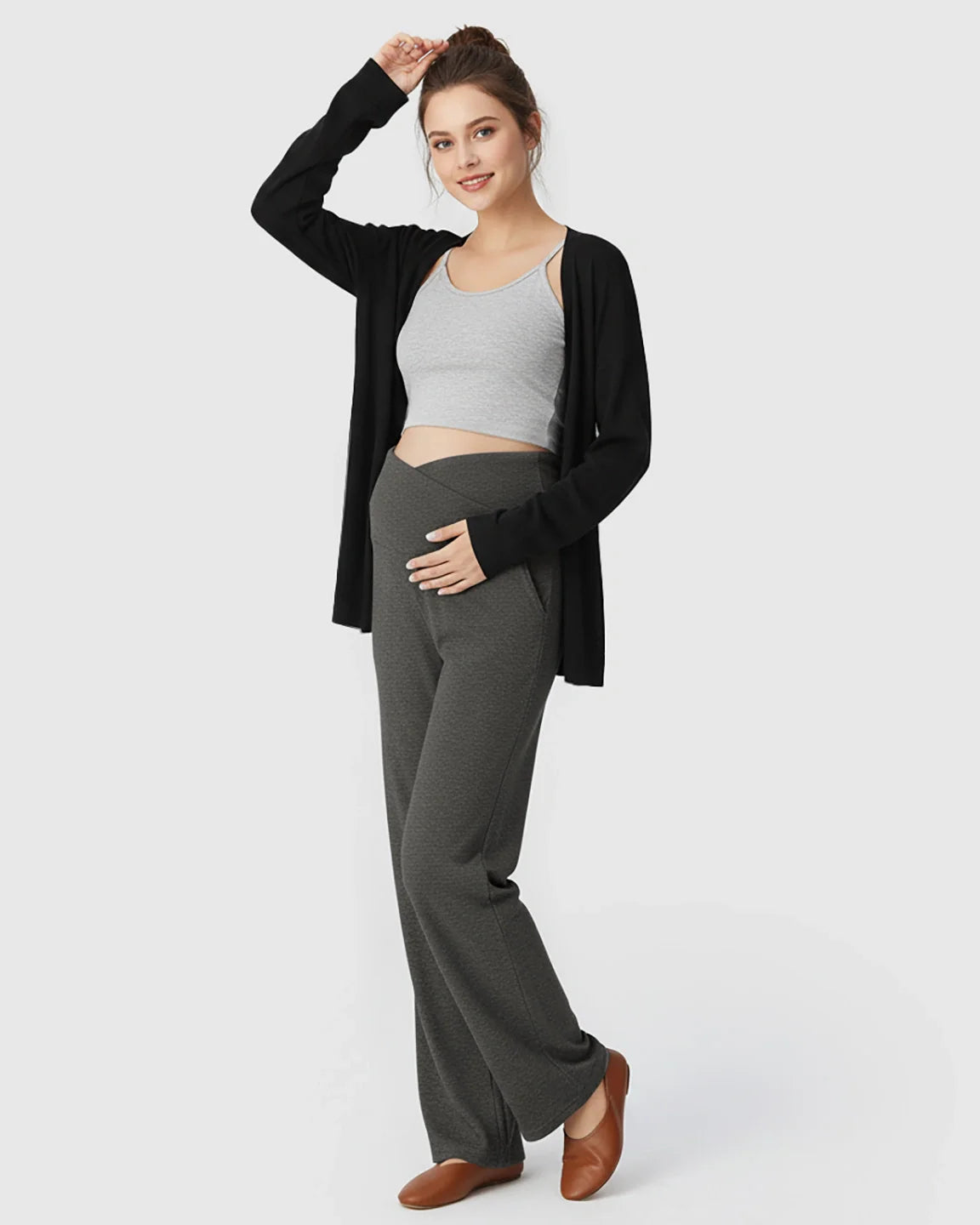 Pregnant woman in charcoal gray crossover waist wide-leg maternity lounge pants, gray crop top, and black cardigan.
