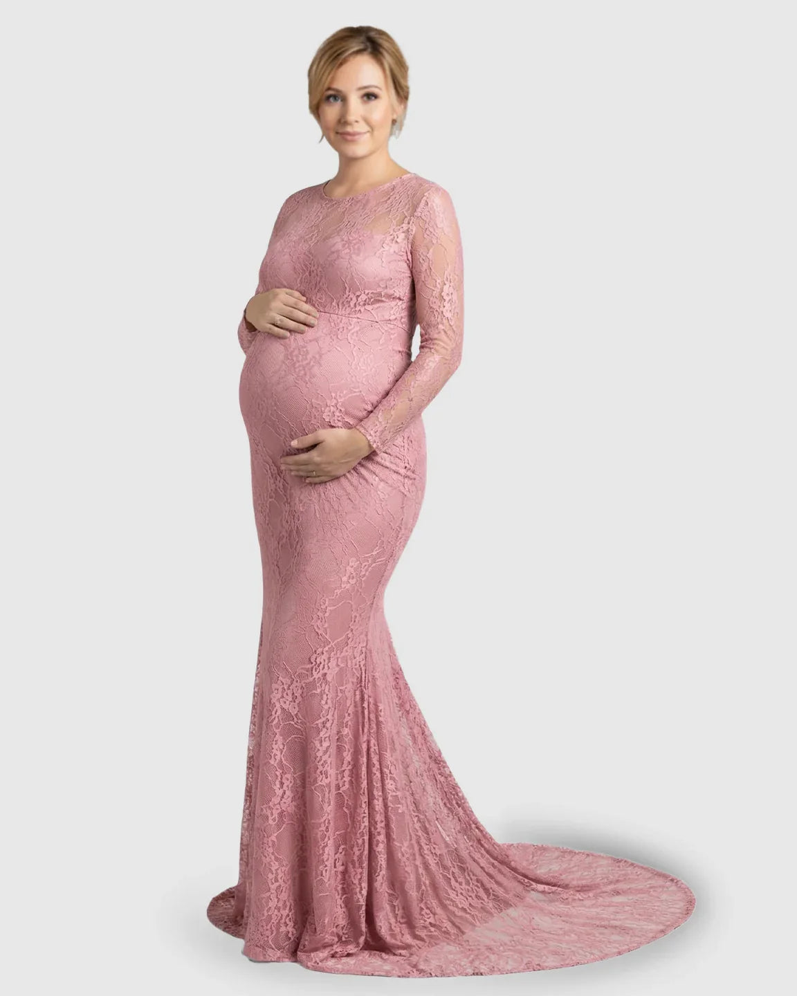 Pink sheer lace trumpet maternity gown with long sleeves and a mermaid-style skirt, worn by a pregnant woman.