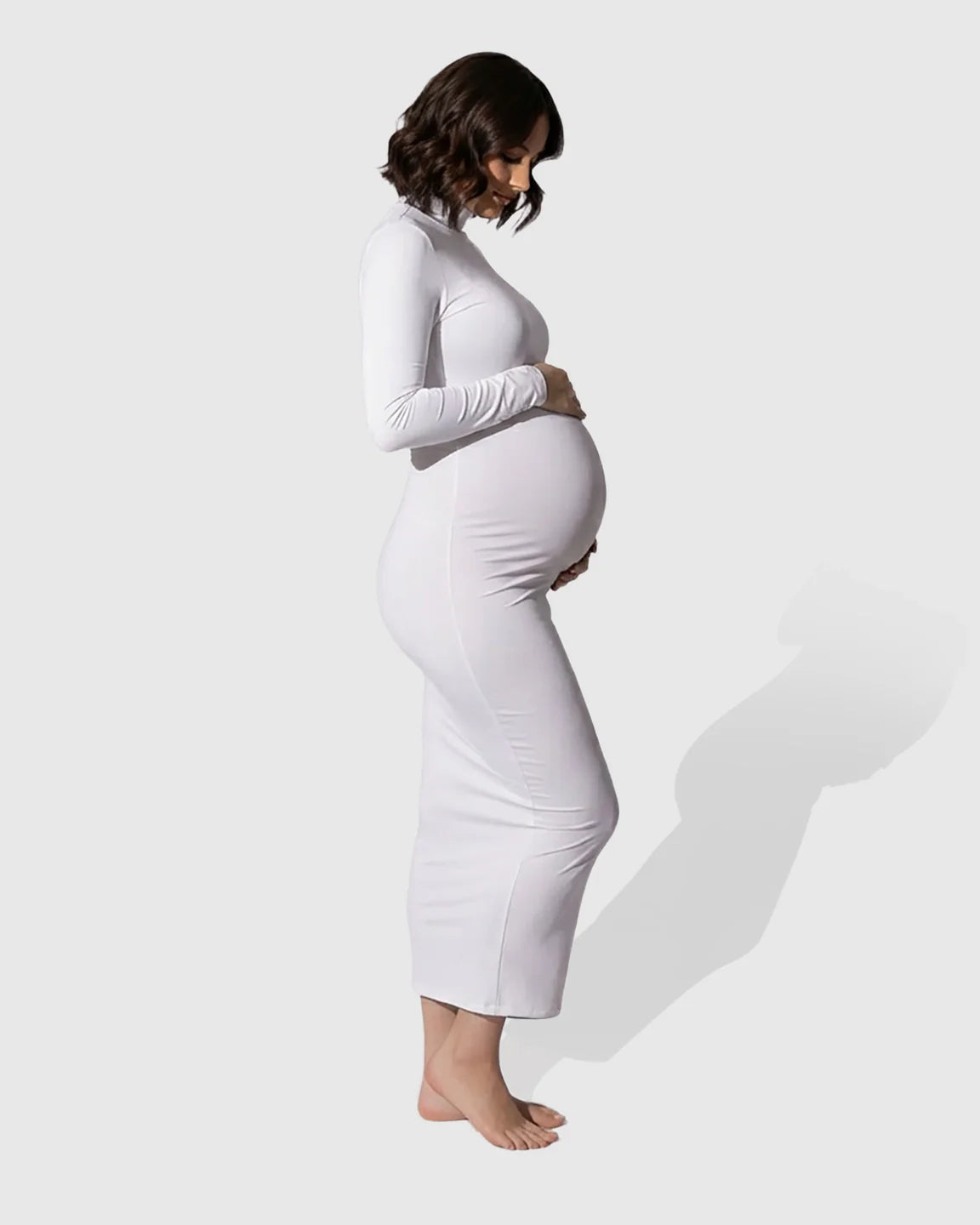 White mock-neck bodycon maternity maxi dress with long sleeves, hugging a pregnant woman's bump.