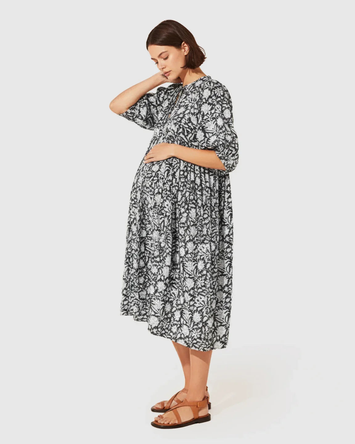 Pregnant woman in a black and white floral loose-fit maternity midi dress with gathered shoulders and puff sleeves.
