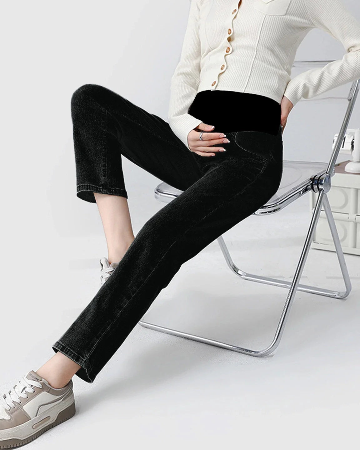 Woman wearing black stretch denim straight-leg maternity jeans with a supportive black belly band.