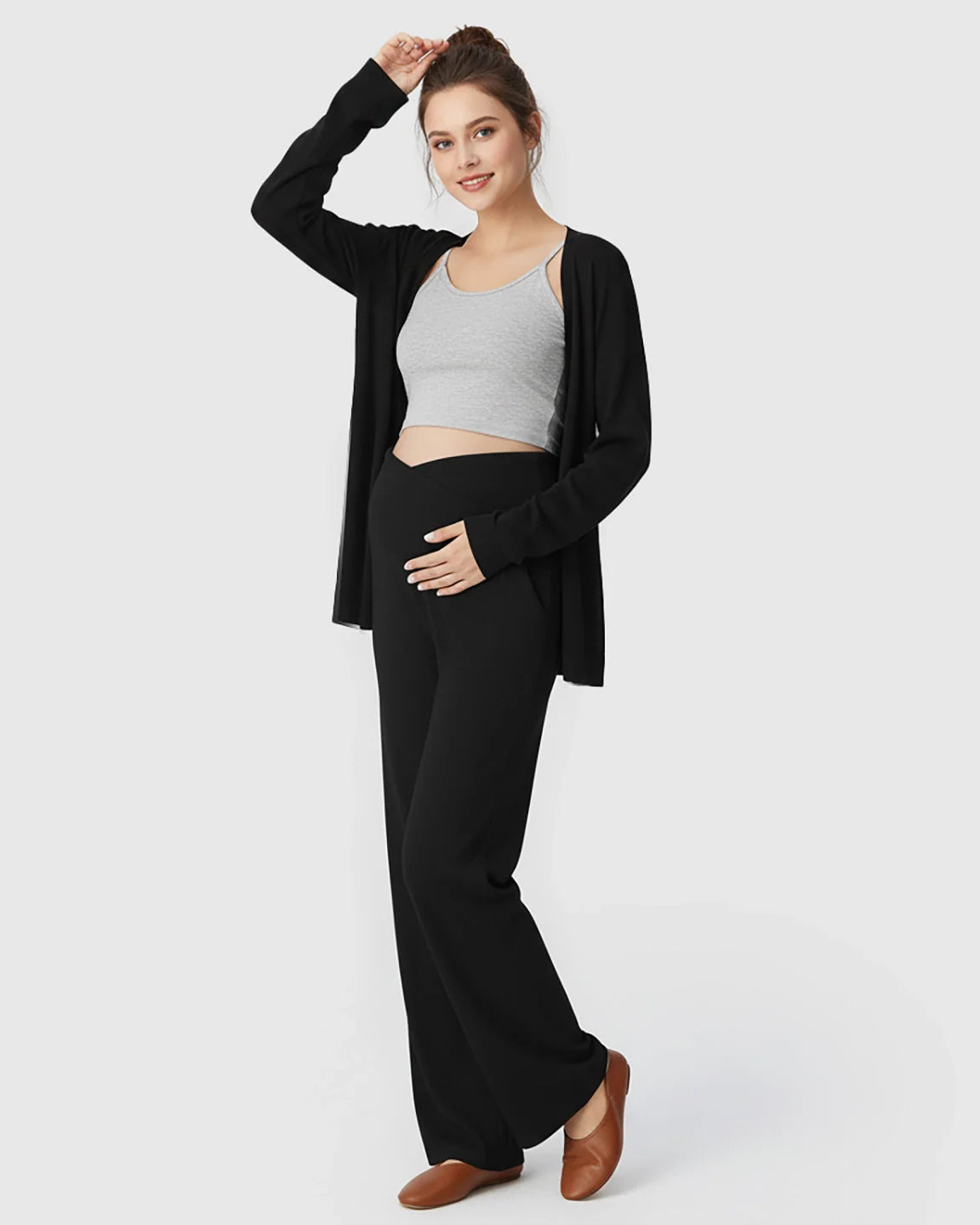 Maternity model in black wide-leg lounge pants with crossover waist, grey crop top, and black cardigan.