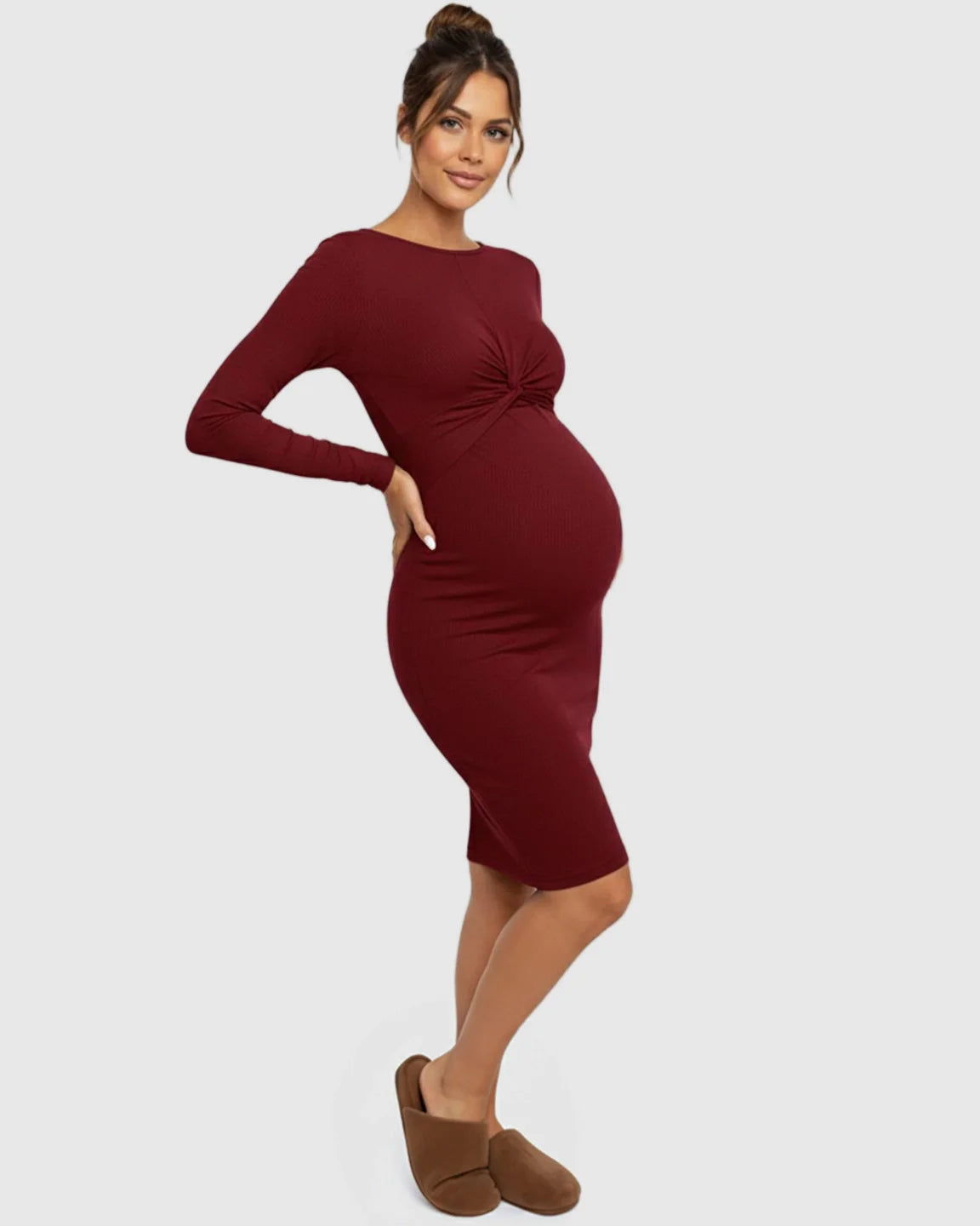 Pregnant woman in a maroon ribbed bodycon maternity dress with a twist-front detail and empire waist.