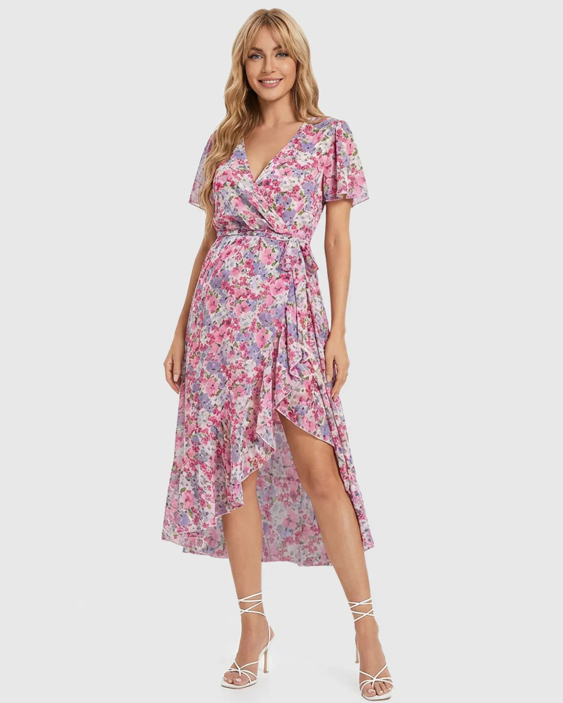 Blonde model in a pink floral V-neck ruffled hem maternity midi dress with a wrap tie waist.