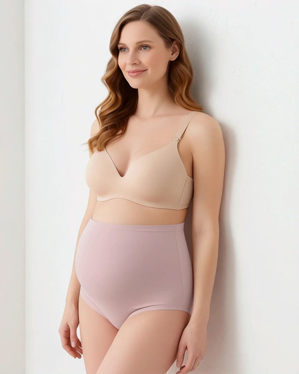 Smiling pregnant woman in a nude maternity bra and high-waist, full-coverage seamless pink briefs.