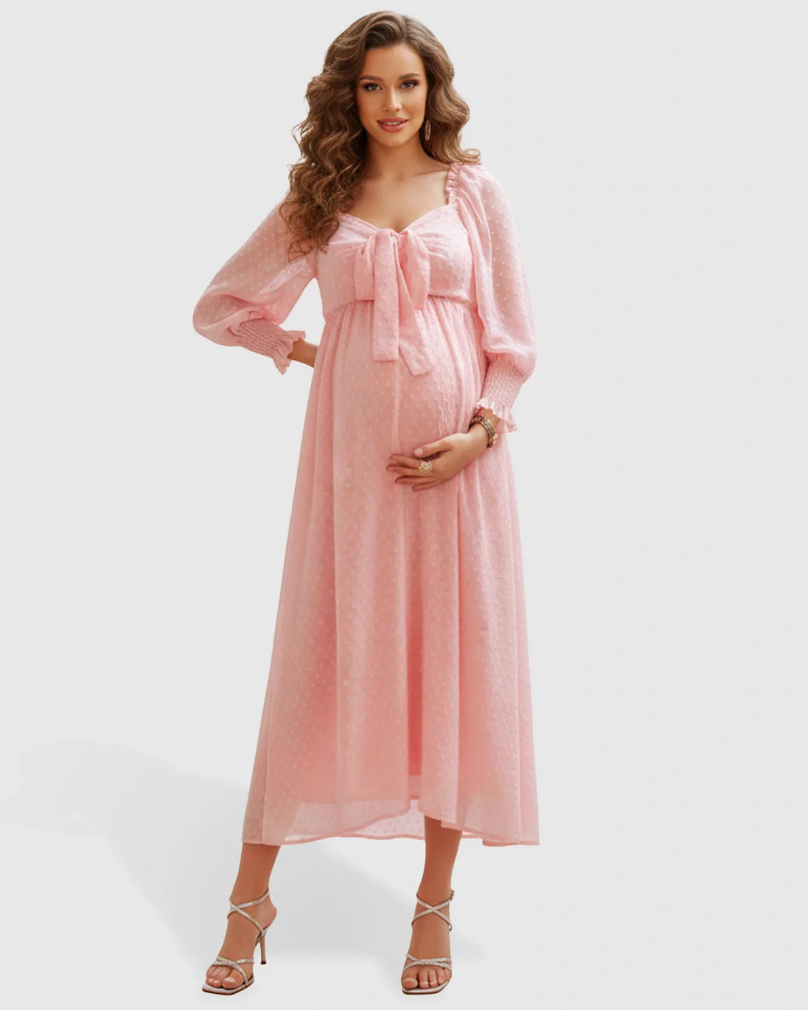 Pregnant woman in a pink polka-dot chiffon long-sleeve maternity maxi dress with a square neckline.