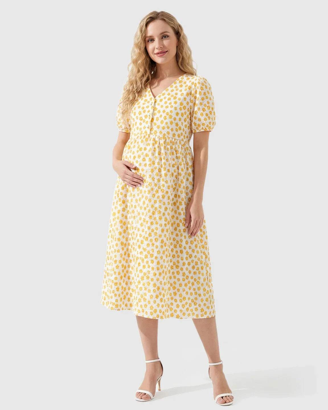 Smiling pregnant woman in a white midi nursing dress with yellow floral print, V-neck, and button-front.