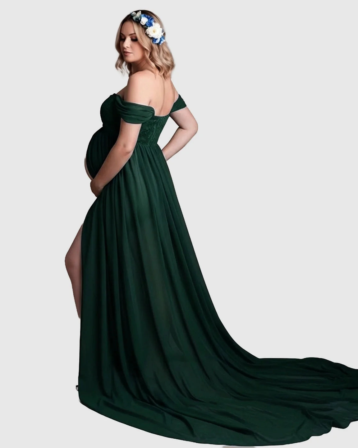Pregnant woman in a dark green off-shoulder chiffon maternity gown with a long train and thigh-high slit.