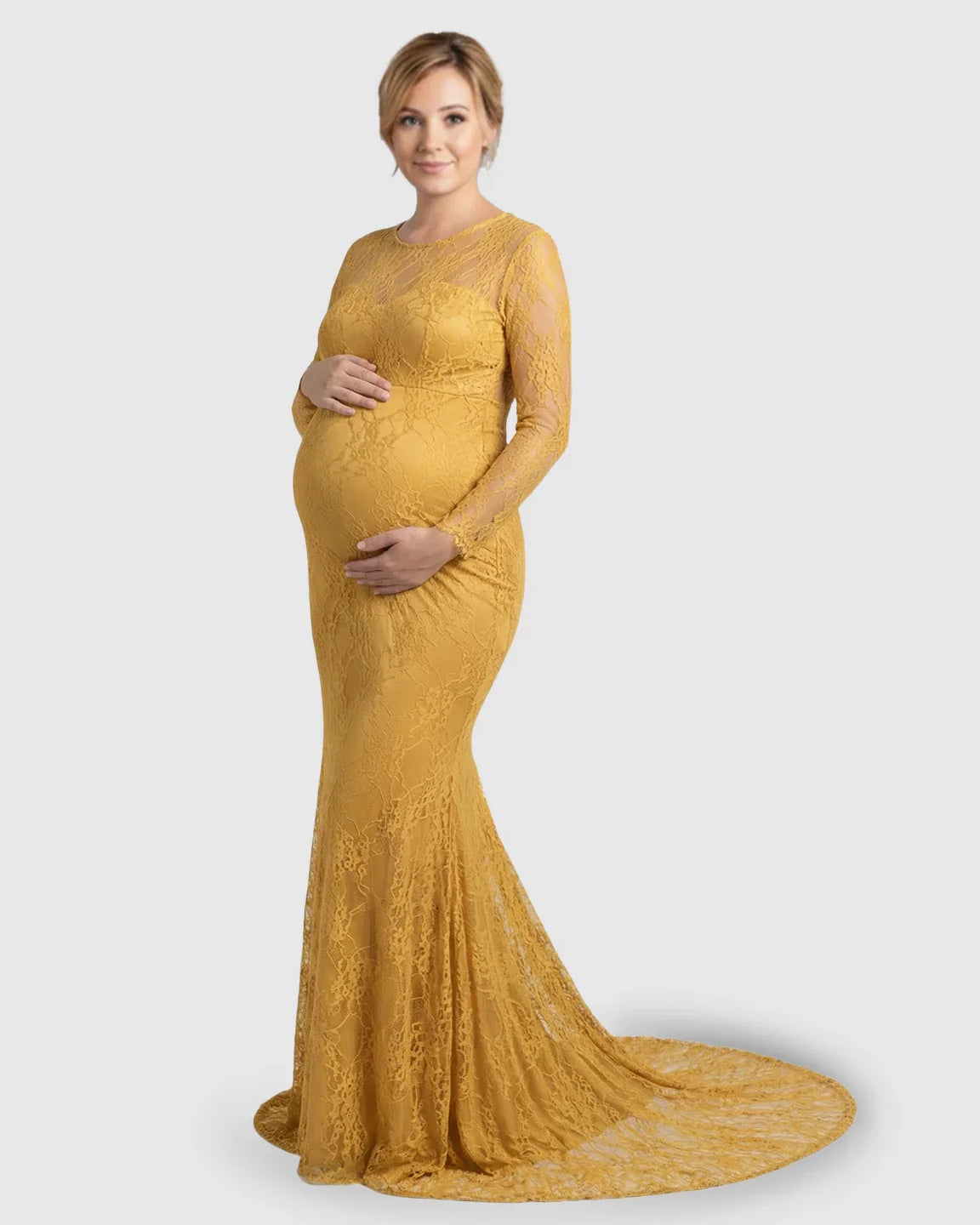 Pregnant woman in a mustard yellow sheer lace trumpet maternity gown with long sleeves and a mermaid skirt.