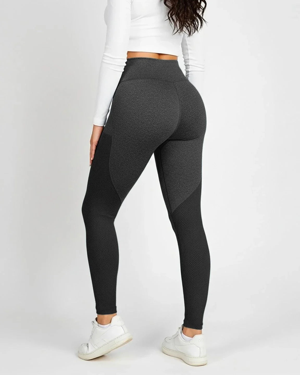 Woman wearing dark gray, high-waisted, body-hugging maternity leggings with textured mesh panels.