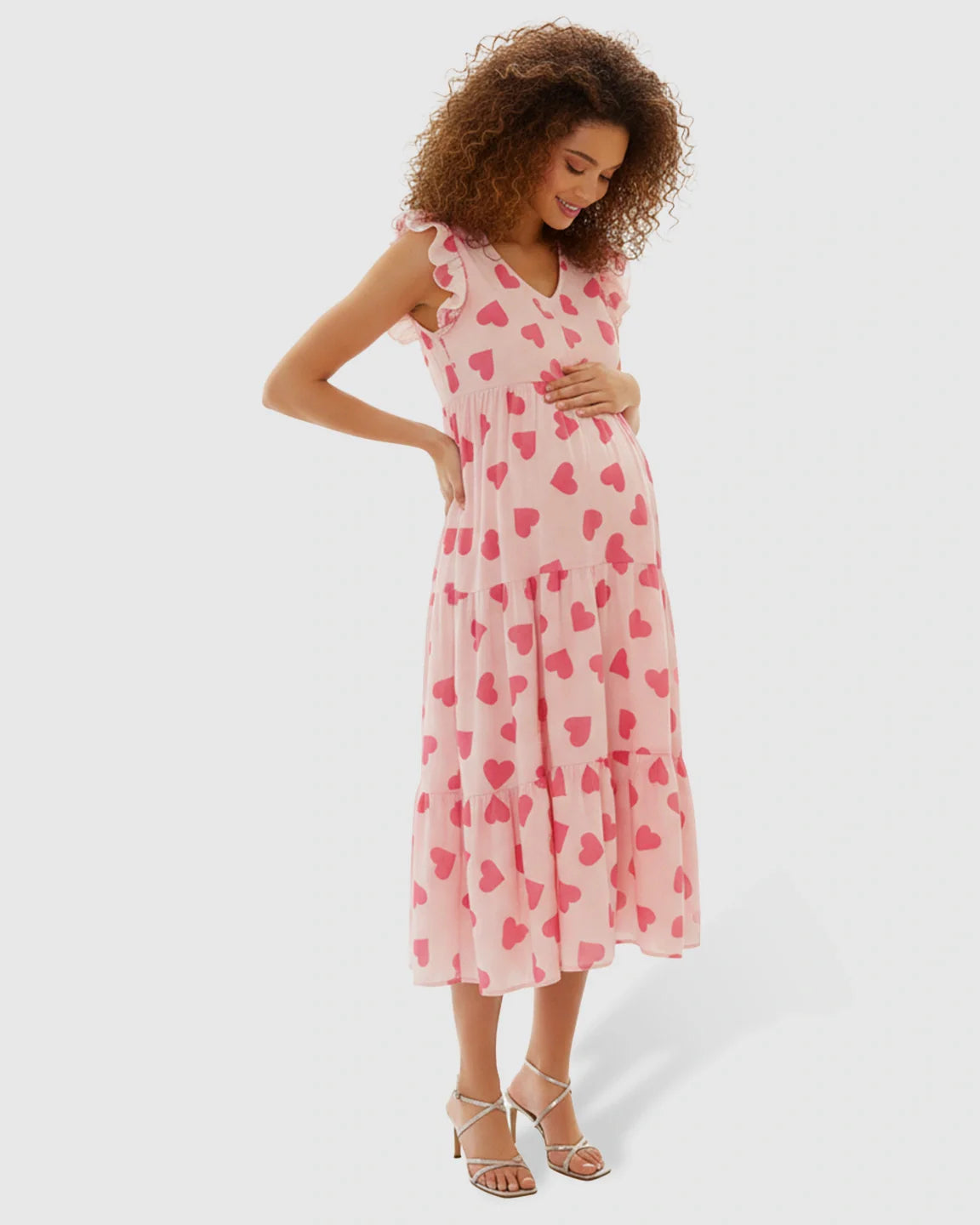 Maternity midi dress in pink chiffon with red heart print, tiered skirt, and ruffle sleeves.