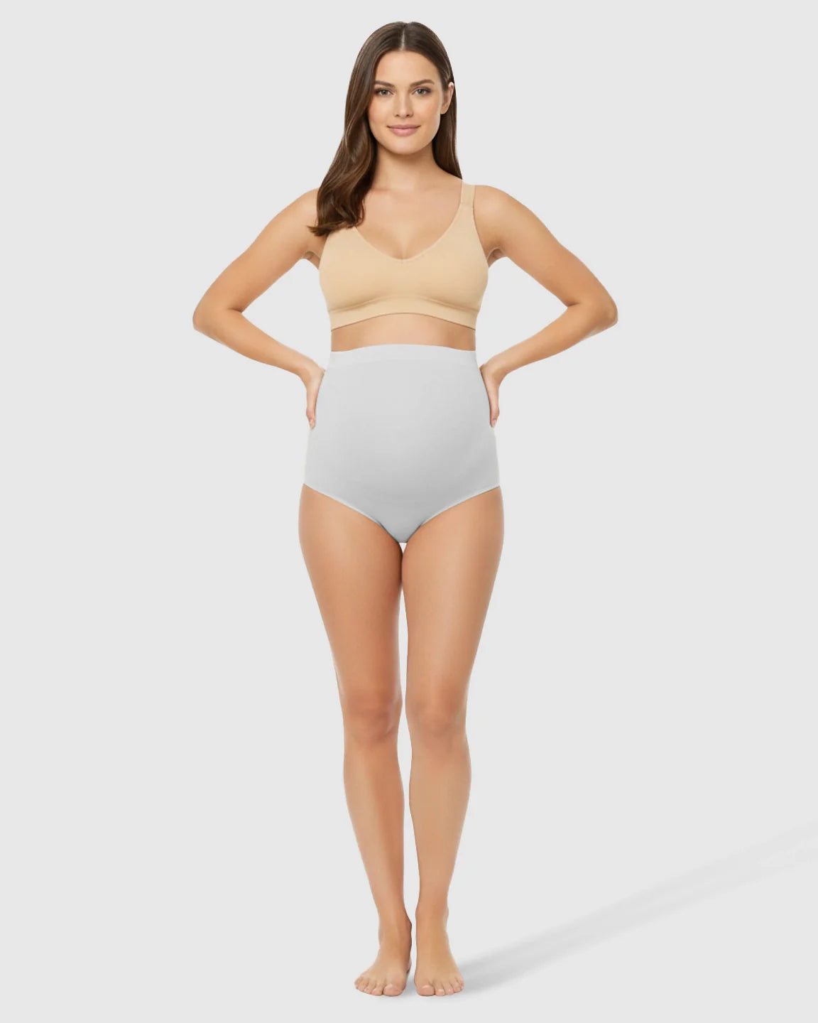 Woman in light grey high-waist seamless belly-support maternity underwear and a nude bra.