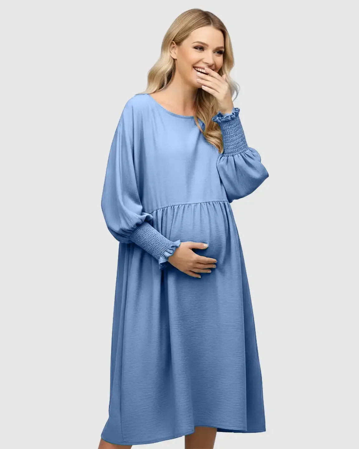 Smiling pregnant woman in a blue smocked sleeve casual maternity dress with a round neckline.
