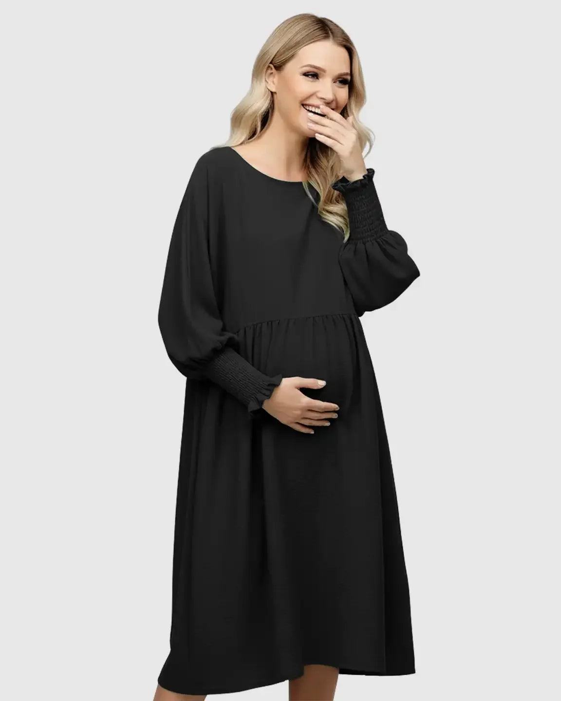 Smiling pregnant woman in a black flowy smocked sleeve casual dress with a round neckline.