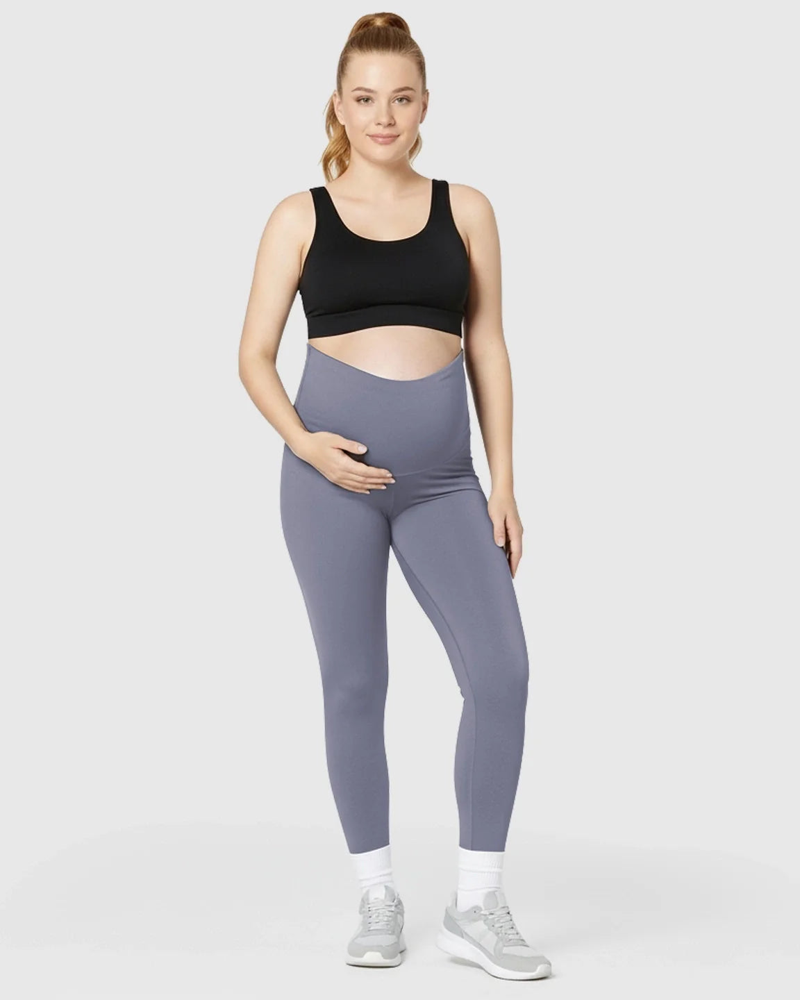 Pregnant woman in ultra-soft, seamless grey maternity midi leggings with a supportive over-the-bump waistband.
