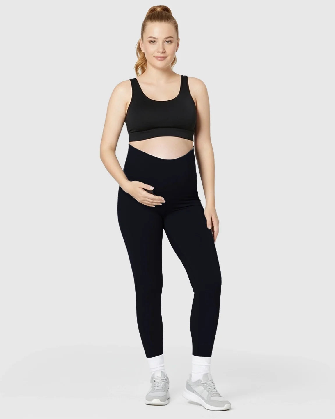 Pregnant woman in black Bump Society Ultra-Soft Support Maternity Midi Leggings and a black sports bra.