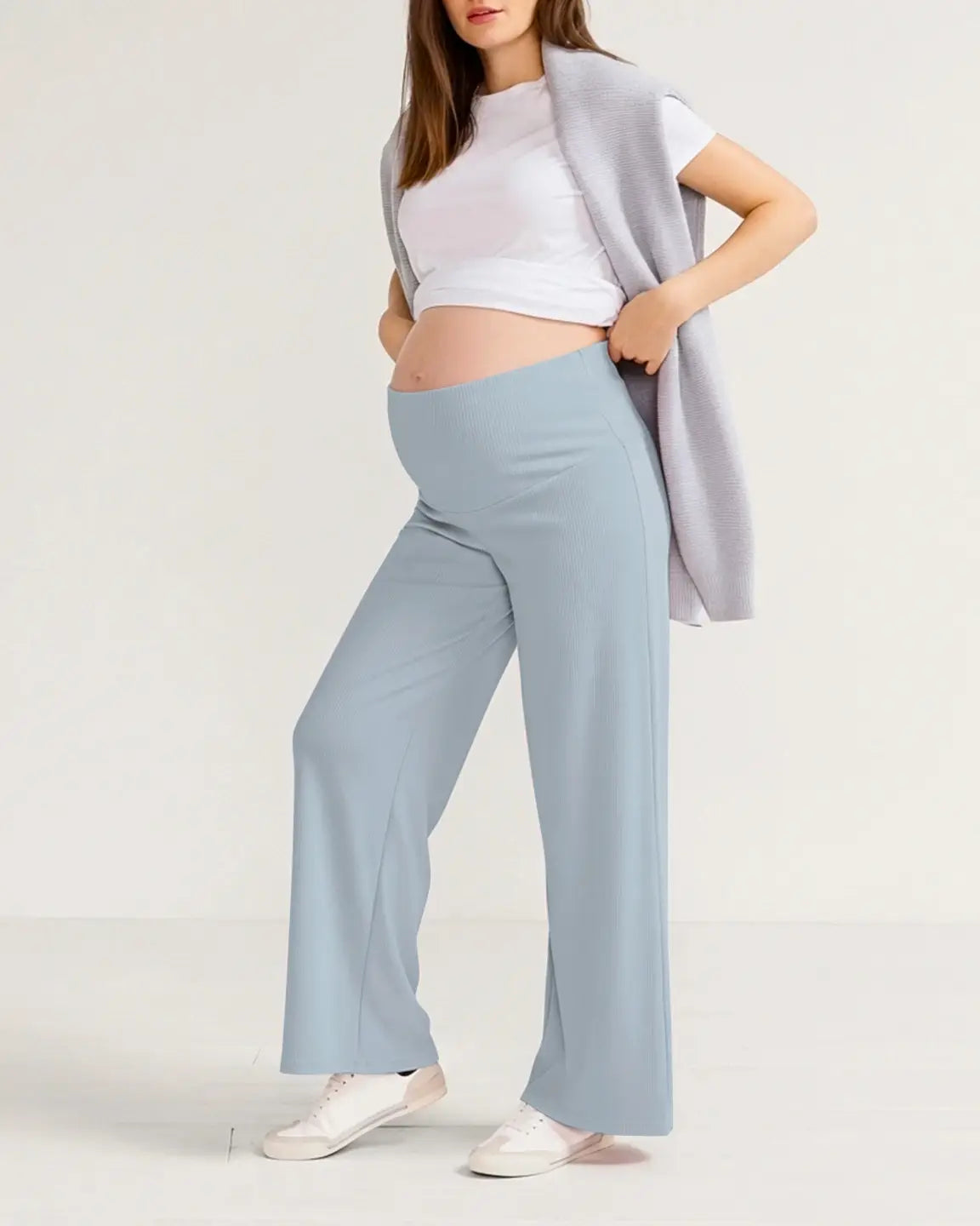 Pregnant woman wearing light blue ribbed wide-leg maternity pants with an over-bump waistband.