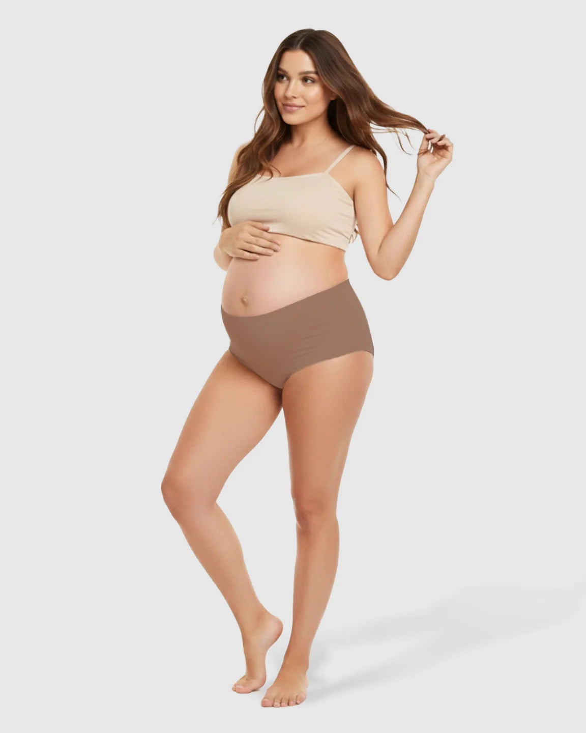 Pregnant woman in seamless high-waist mocha maternity support underwear and a beige crop top.