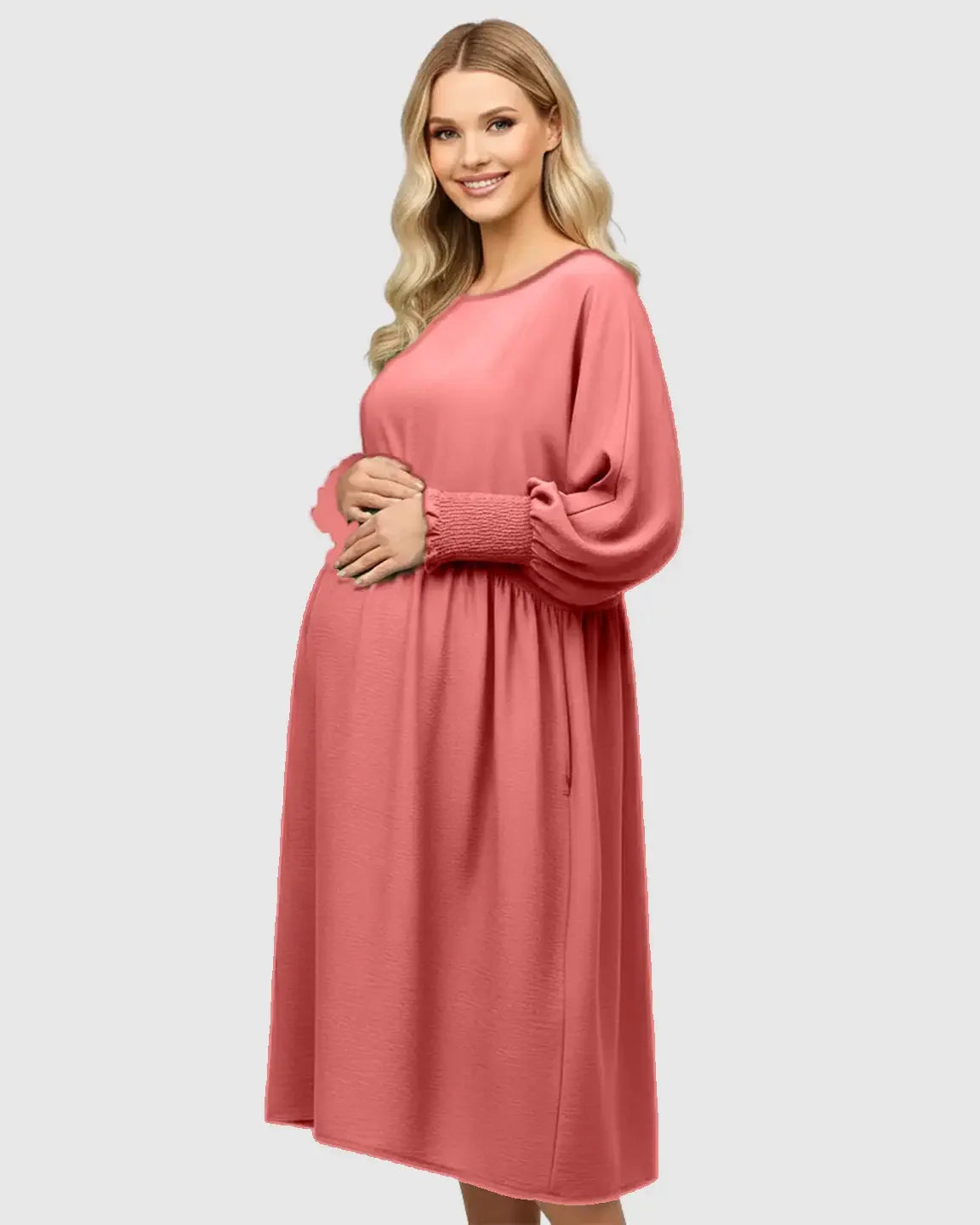 Smiling pregnant woman in a coral smocked-sleeve maternity dress with a round neck and drawstring waist.