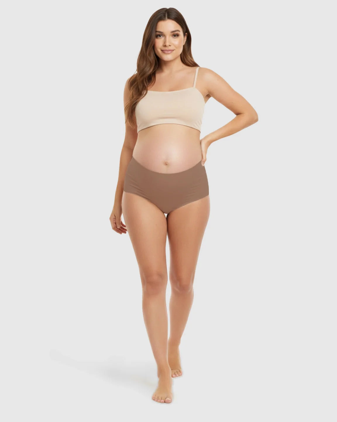 Pregnant woman wearing seamless high-waist support maternity underwear in brown and a beige crop top.
