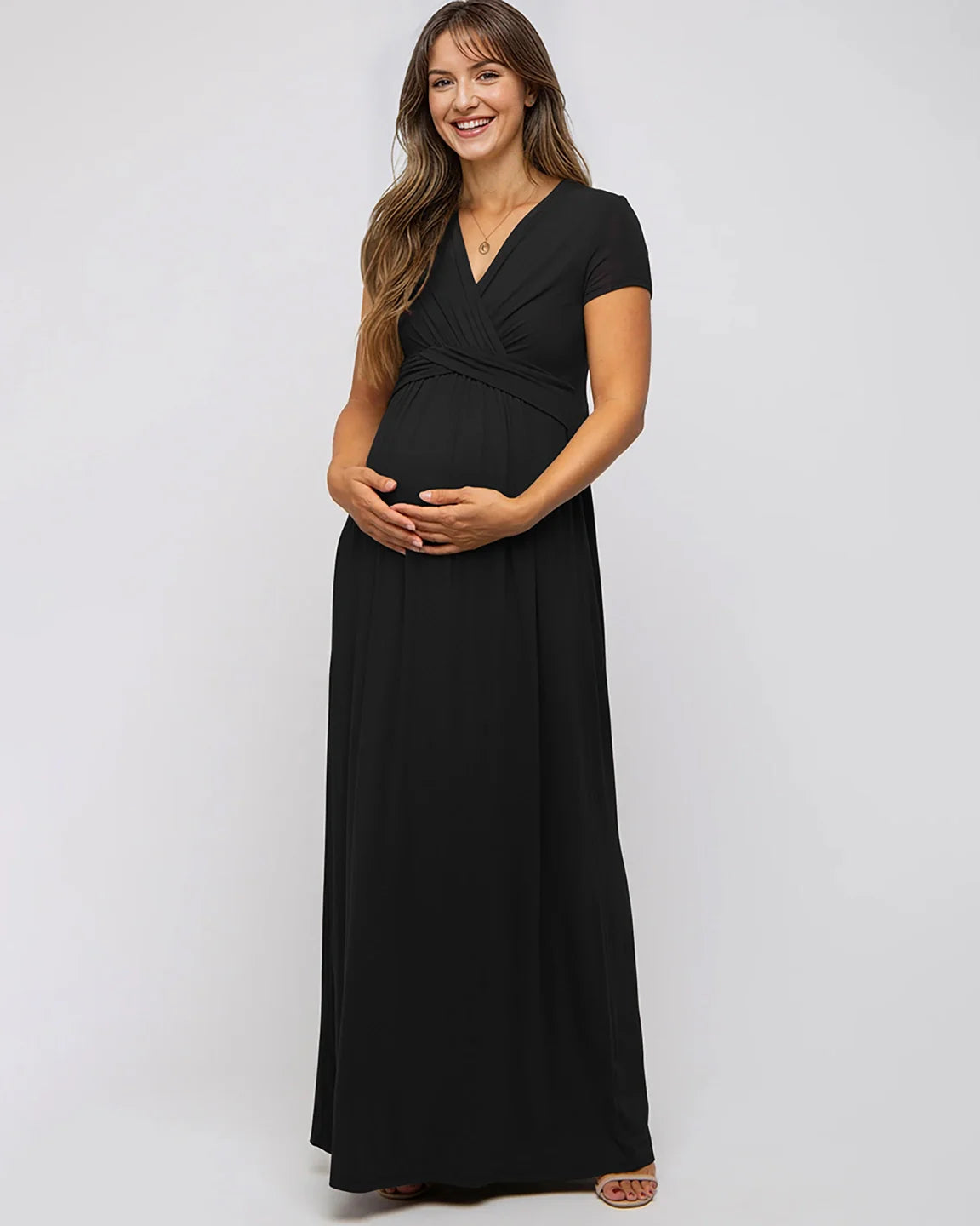 Smiling pregnant woman in a black Twist Front Draped Maternity Nursing Maxi Dress with short sleeves.