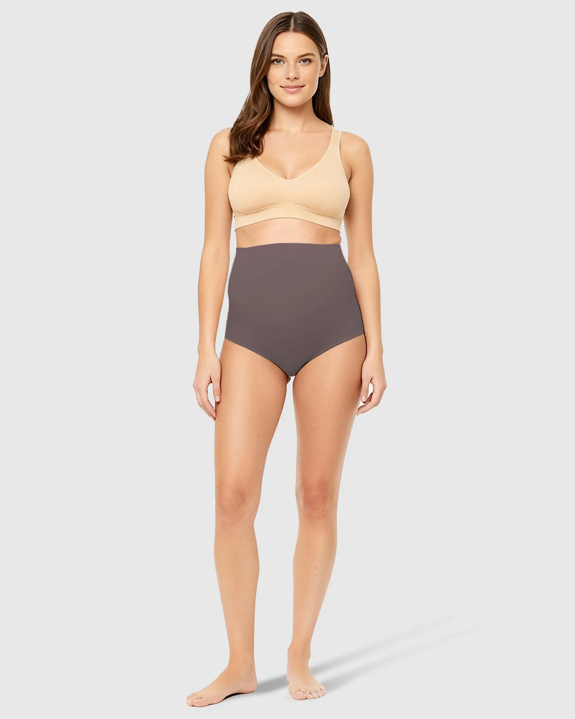 Woman in Bump Society high-waist seamless belly-support maternity underwear in charcoal gray.