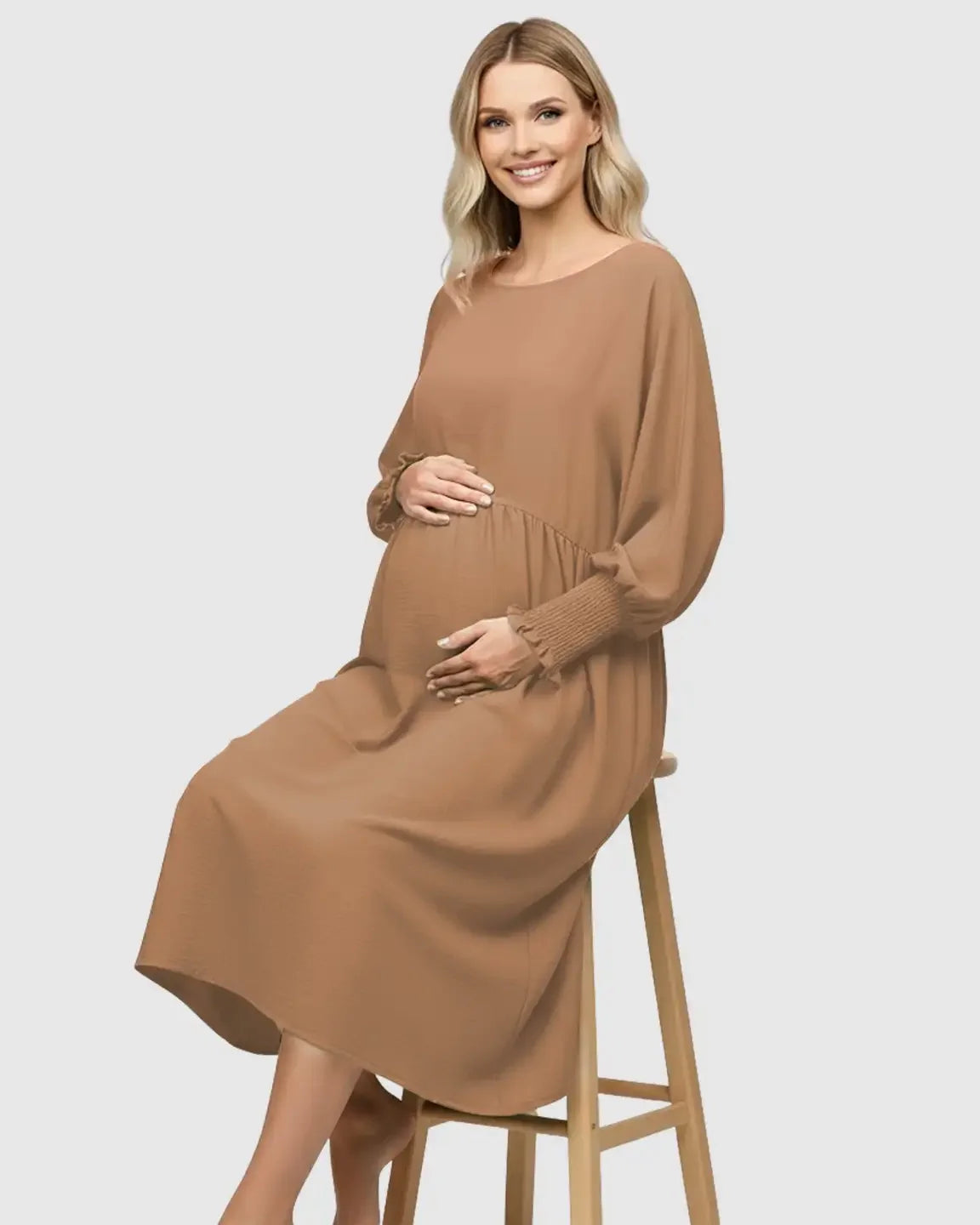 Smiling pregnant woman in a brown flowy smocked sleeve casual dress with a round neckline.