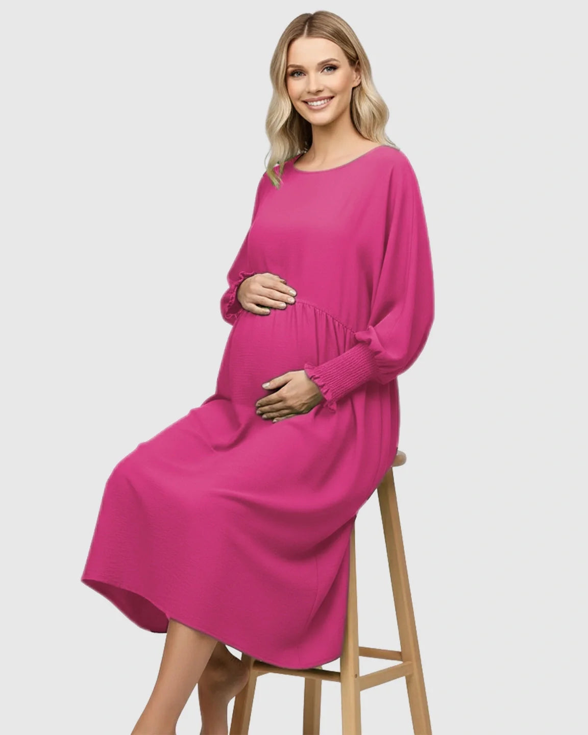 Smiling pregnant woman in a fuchsia smocked-sleeve casual dress with a round neckline and drawstring waist.