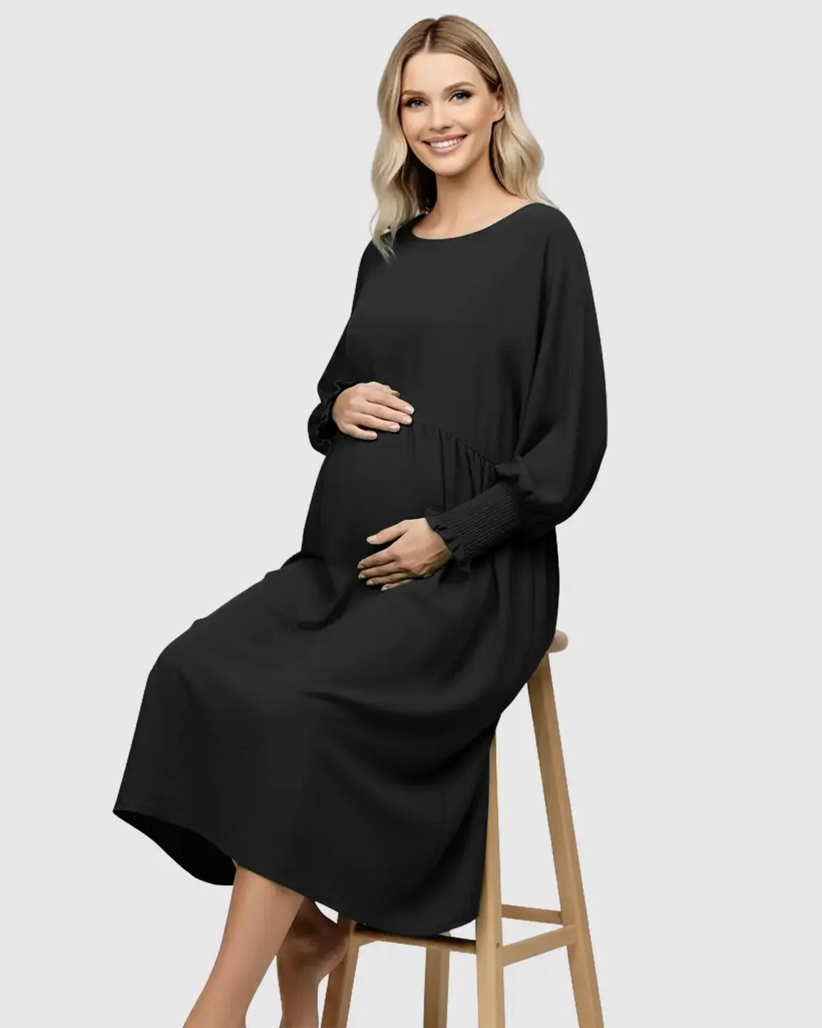 Smiling pregnant woman in a black flowy smocked sleeve casual dress with a round neckline and drawstring waist.