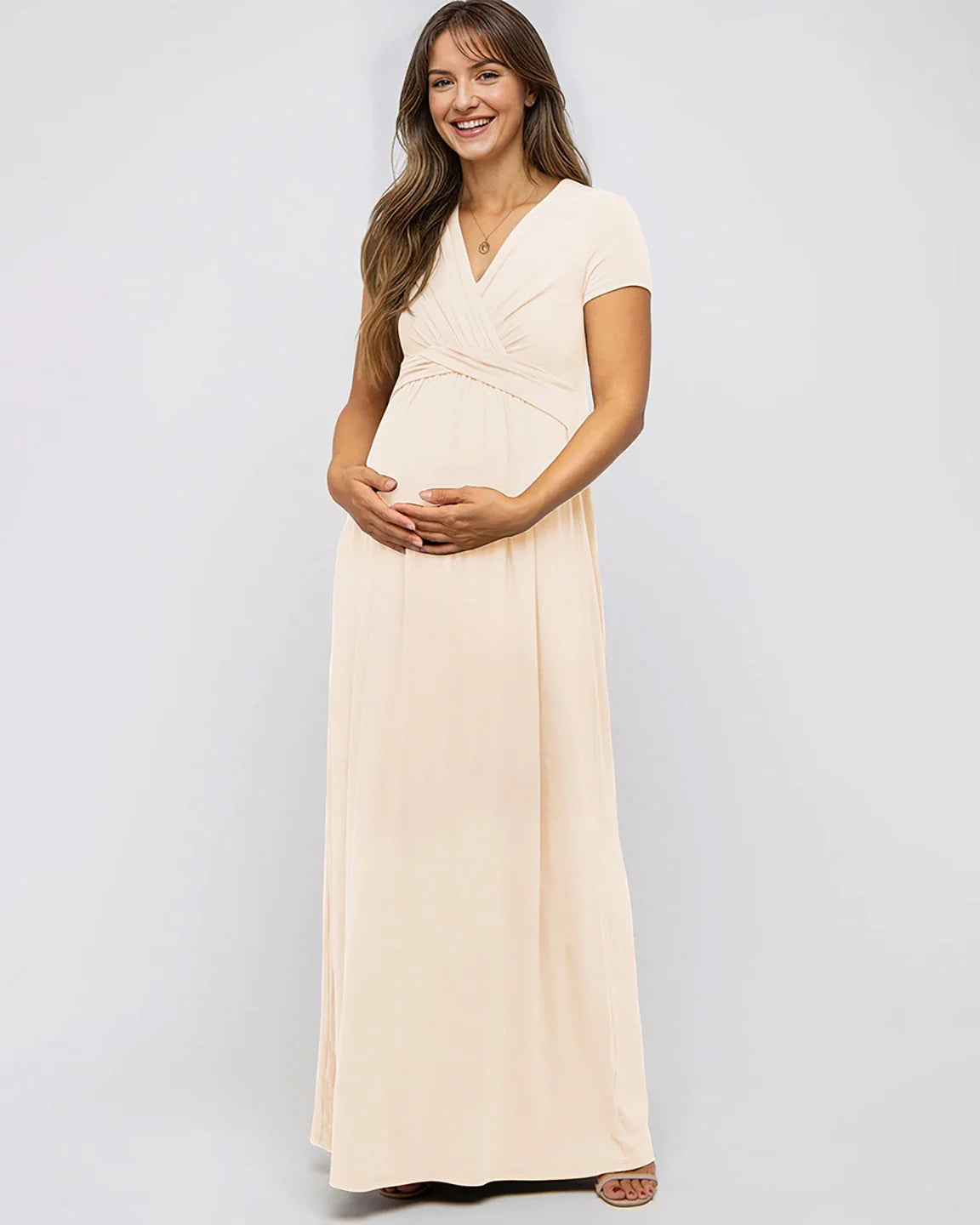 Smiling pregnant woman in a peach Twist Front Draped Maternity Nursing Maxi Dress with short sleeves.