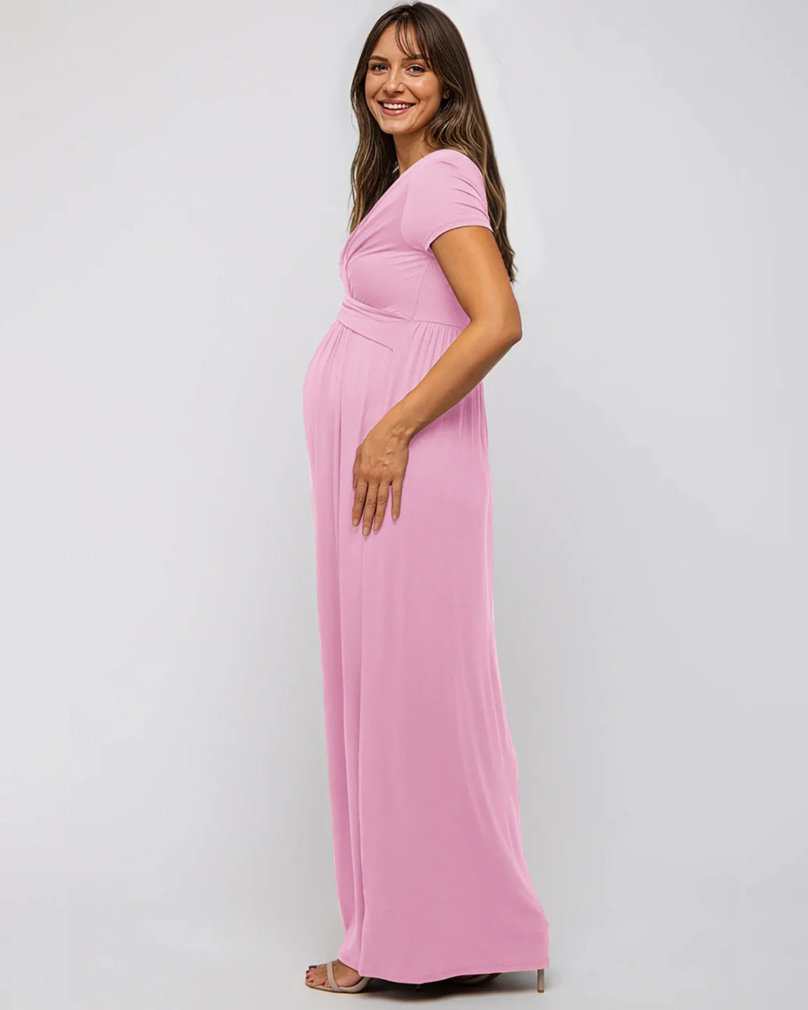 Smiling pregnant woman in a pink twist-front draped maternity nursing maxi dress.