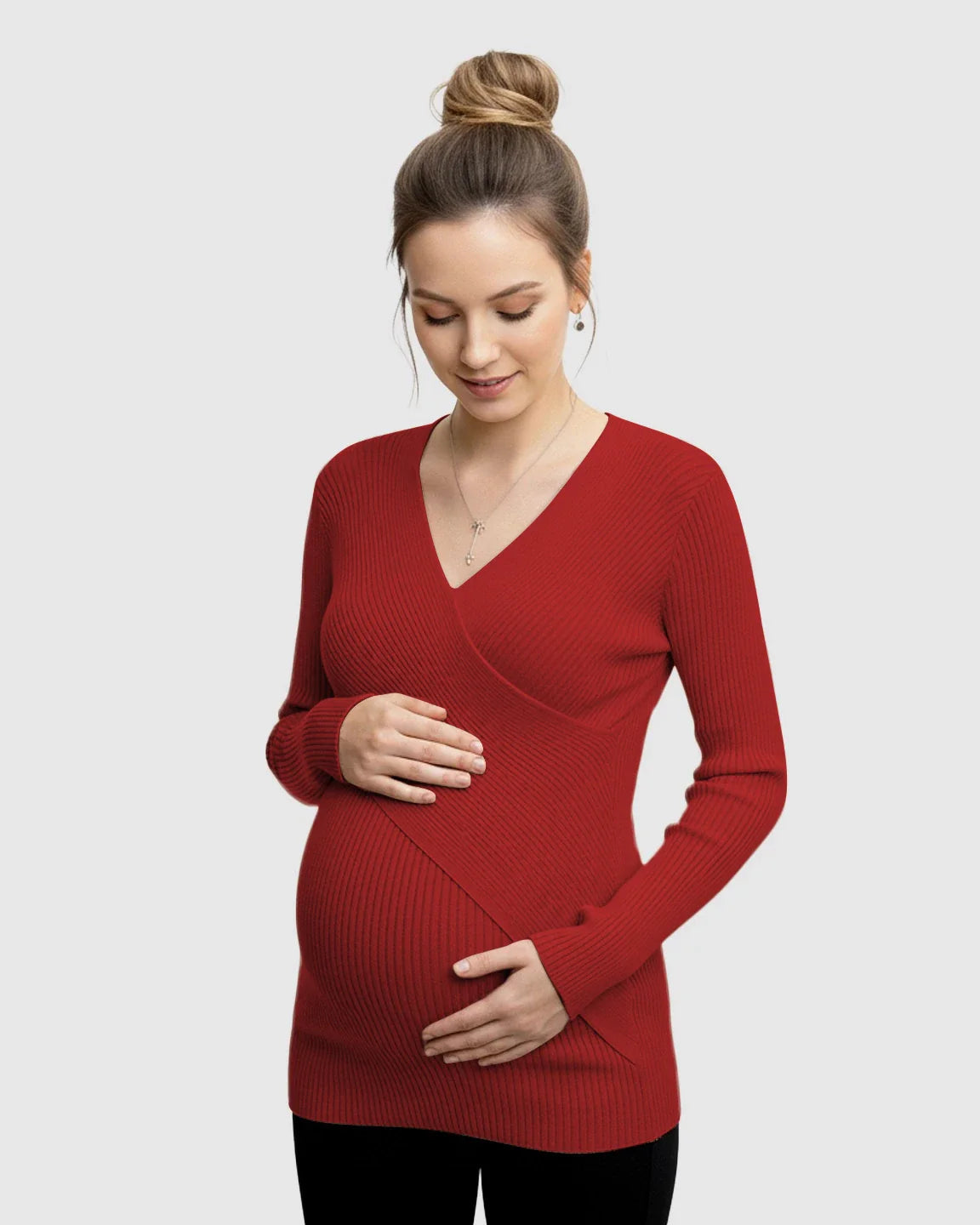 Pregnant woman in a red faux-wrap ribbed maternity top, holding her bump.