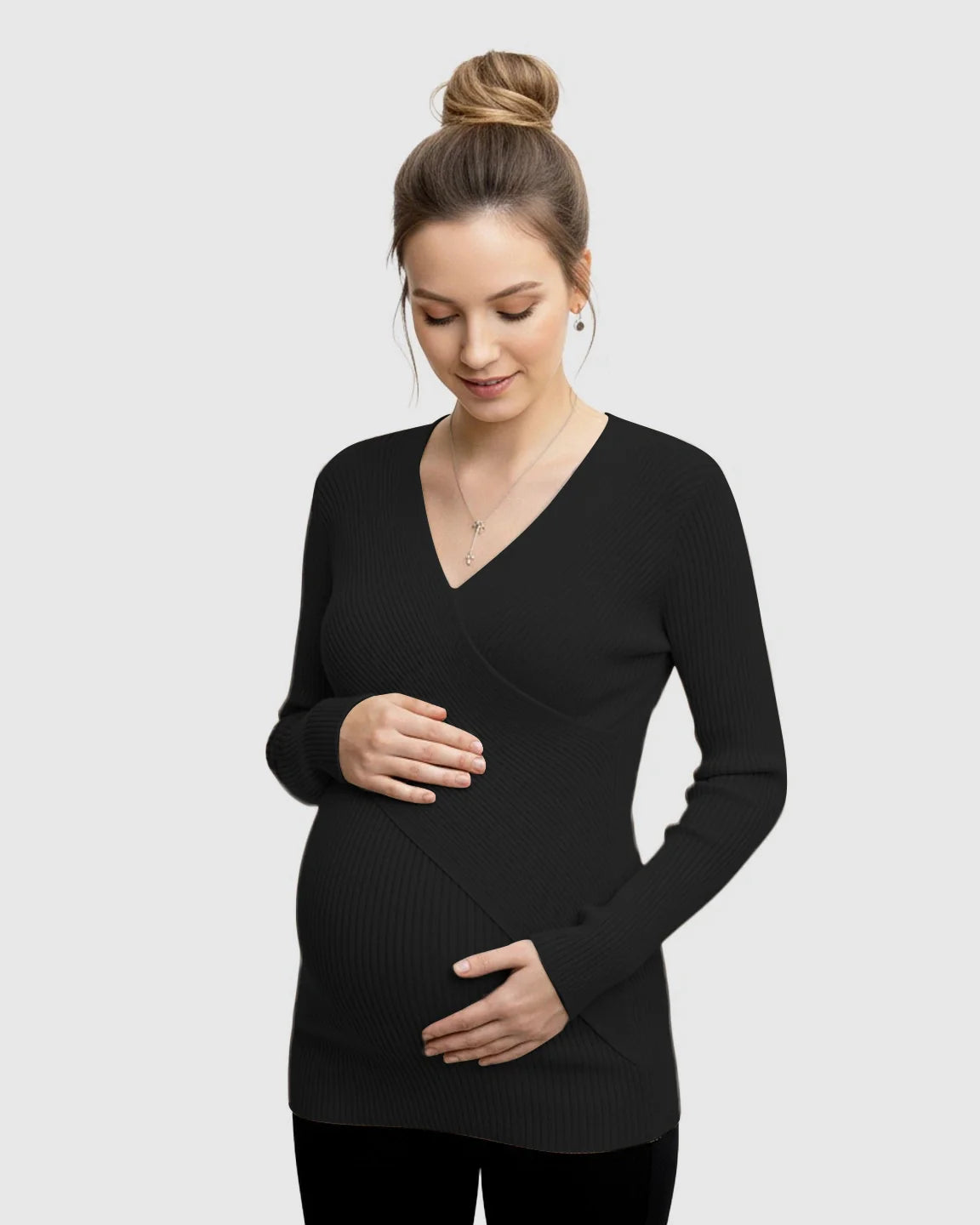 Pregnant woman in a black faux-wrap ribbed maternity top, gently holding her bump.