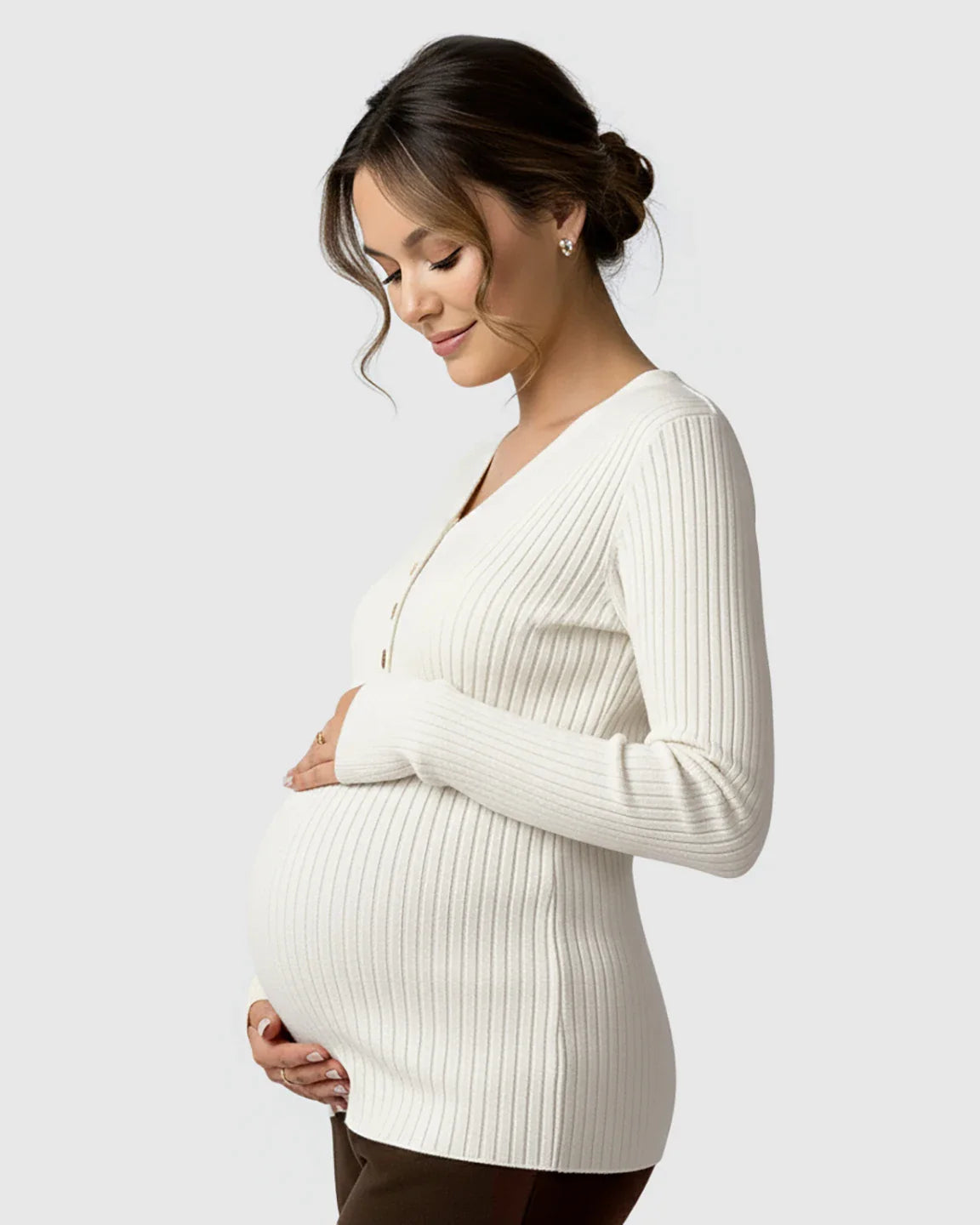 Pregnant woman in a cream ribbed V-neck maternity nursing sweater with button details, cradling her belly.