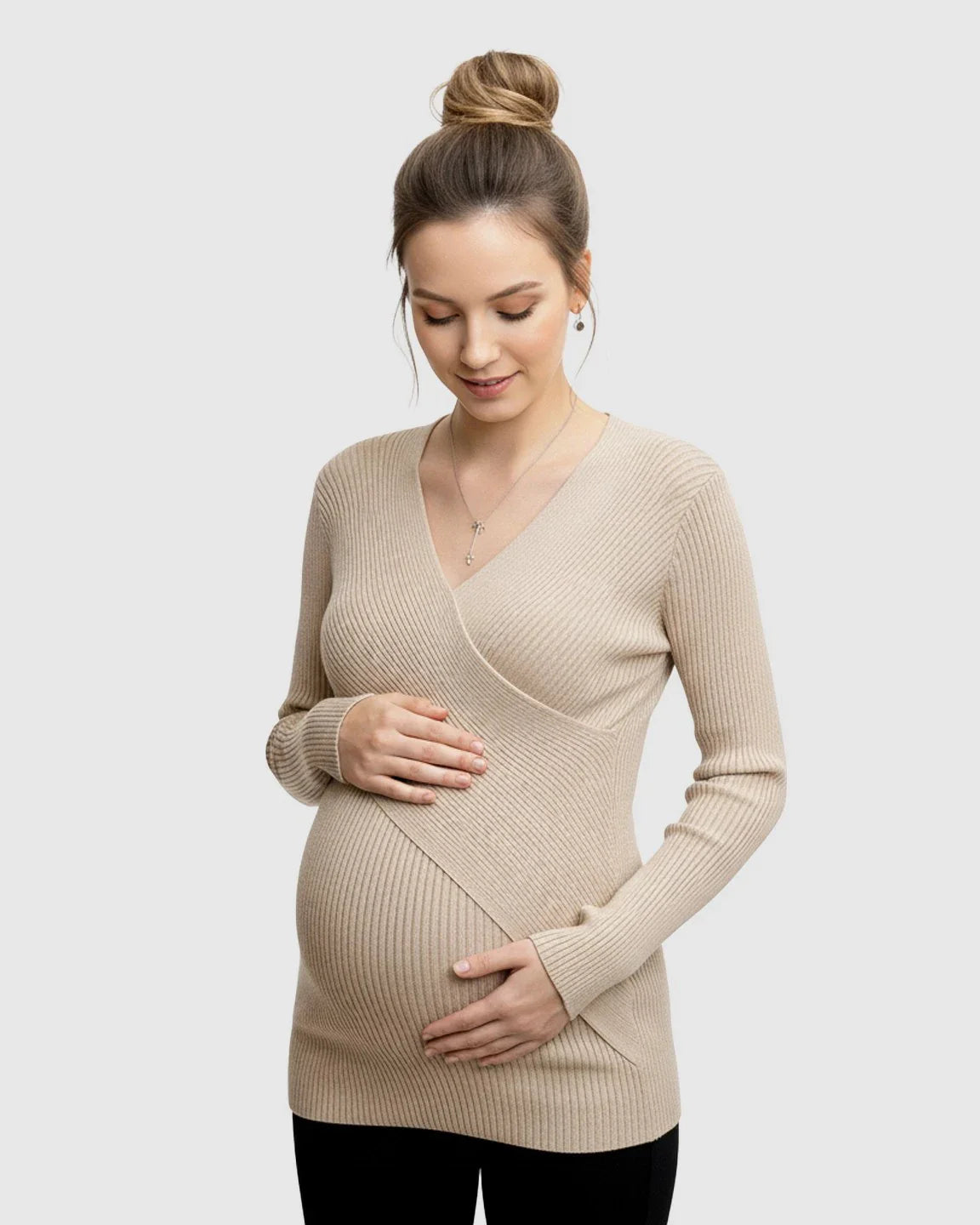 Pregnant woman in a beige faux-wrap ribbed maternity top, gently holding her bump.