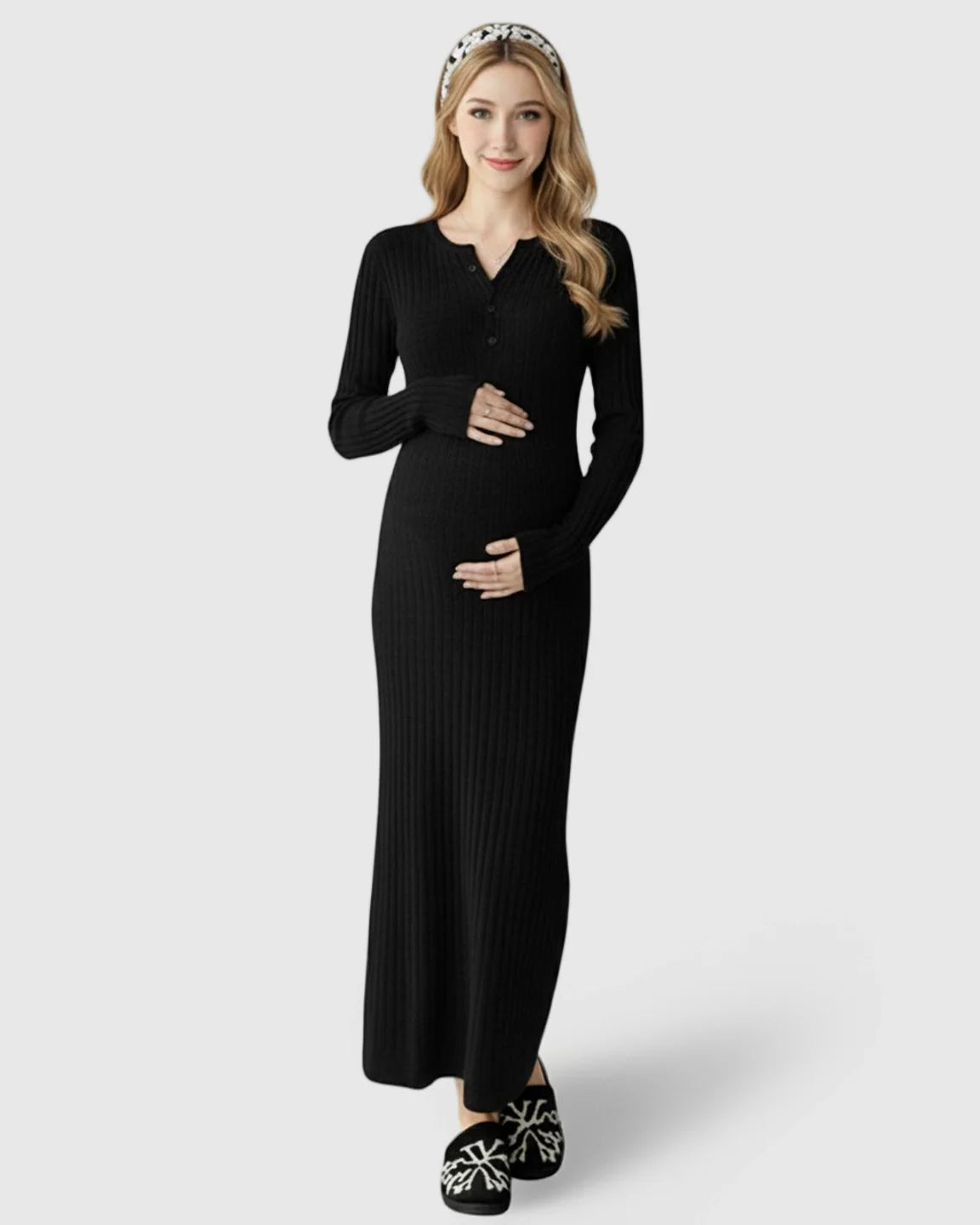 Smiling pregnant woman in a black ribbed knit long-sleeve maternity maxi dress, hands on bump.
