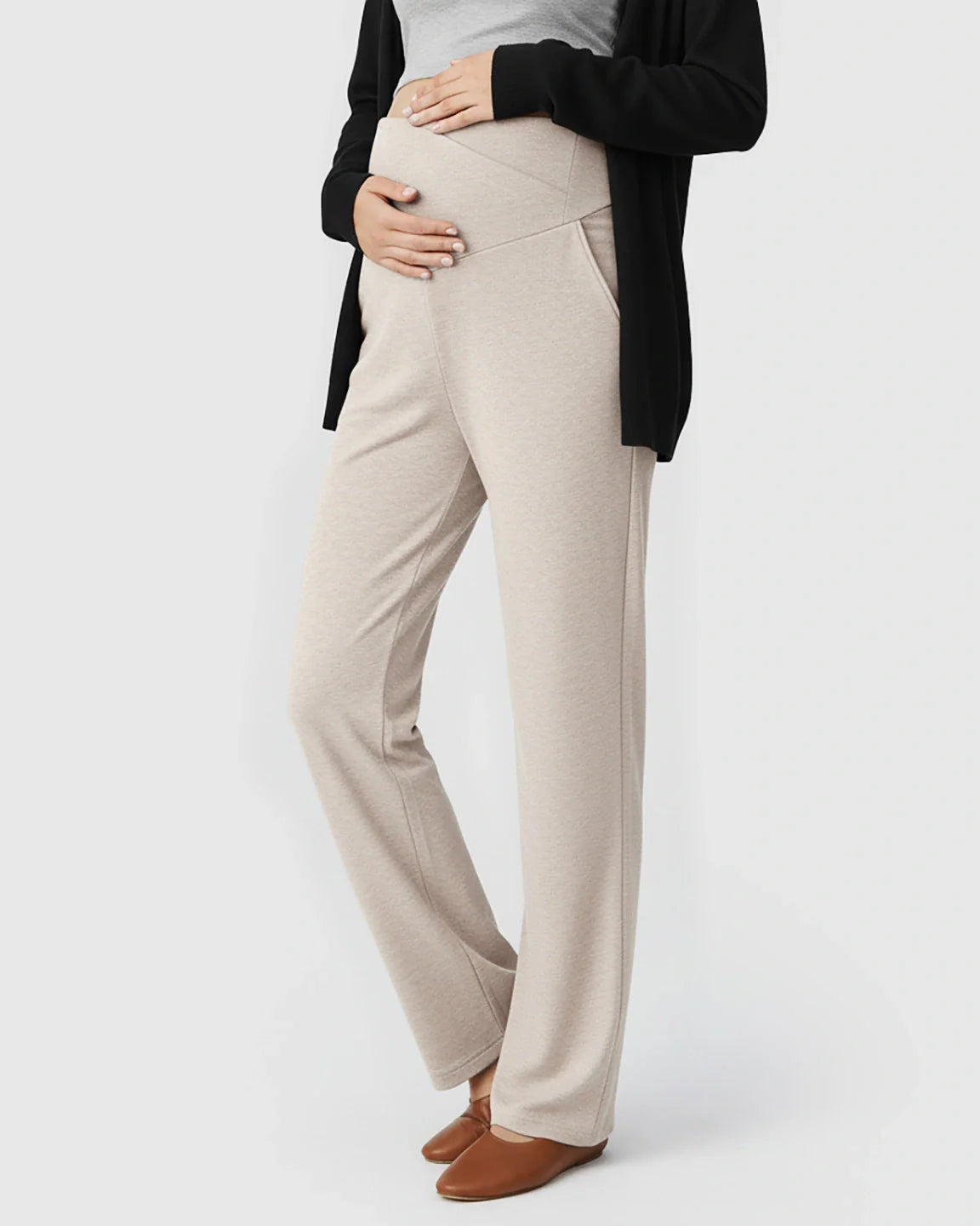 Pregnant woman in beige crossover waist wide-leg maternity lounge pants with side pockets.