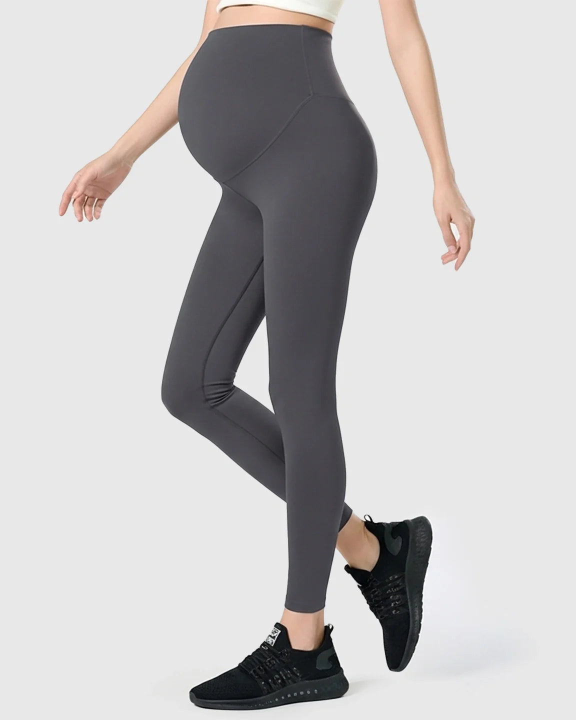 Maternity leggings in dark gray with a high-waisted, double-layer belly support panel, worn by a pregnant woman.