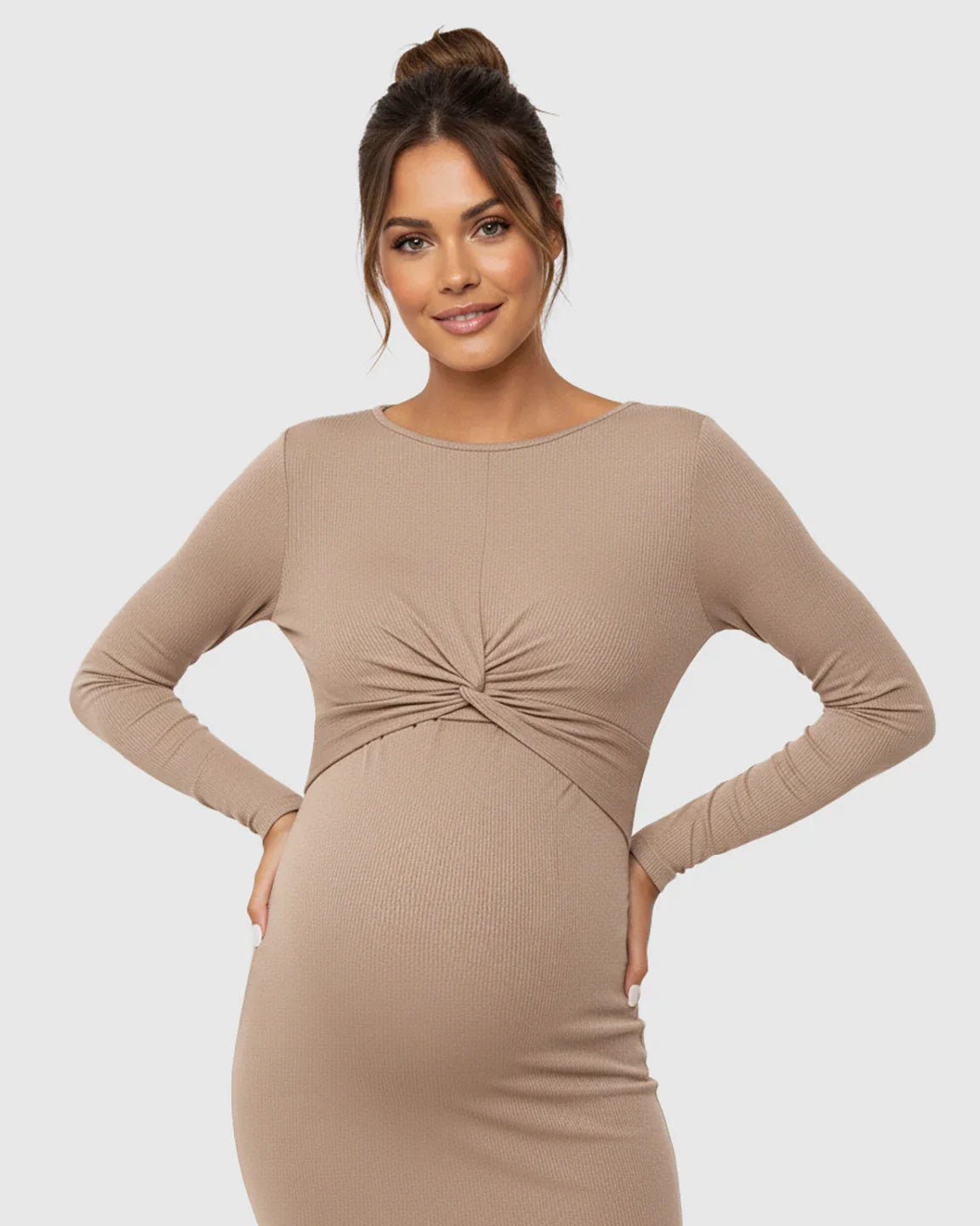 Woman in a long-sleeve, ribbed, tan maternity bodycon dress with a twist-front detail and empire waist.