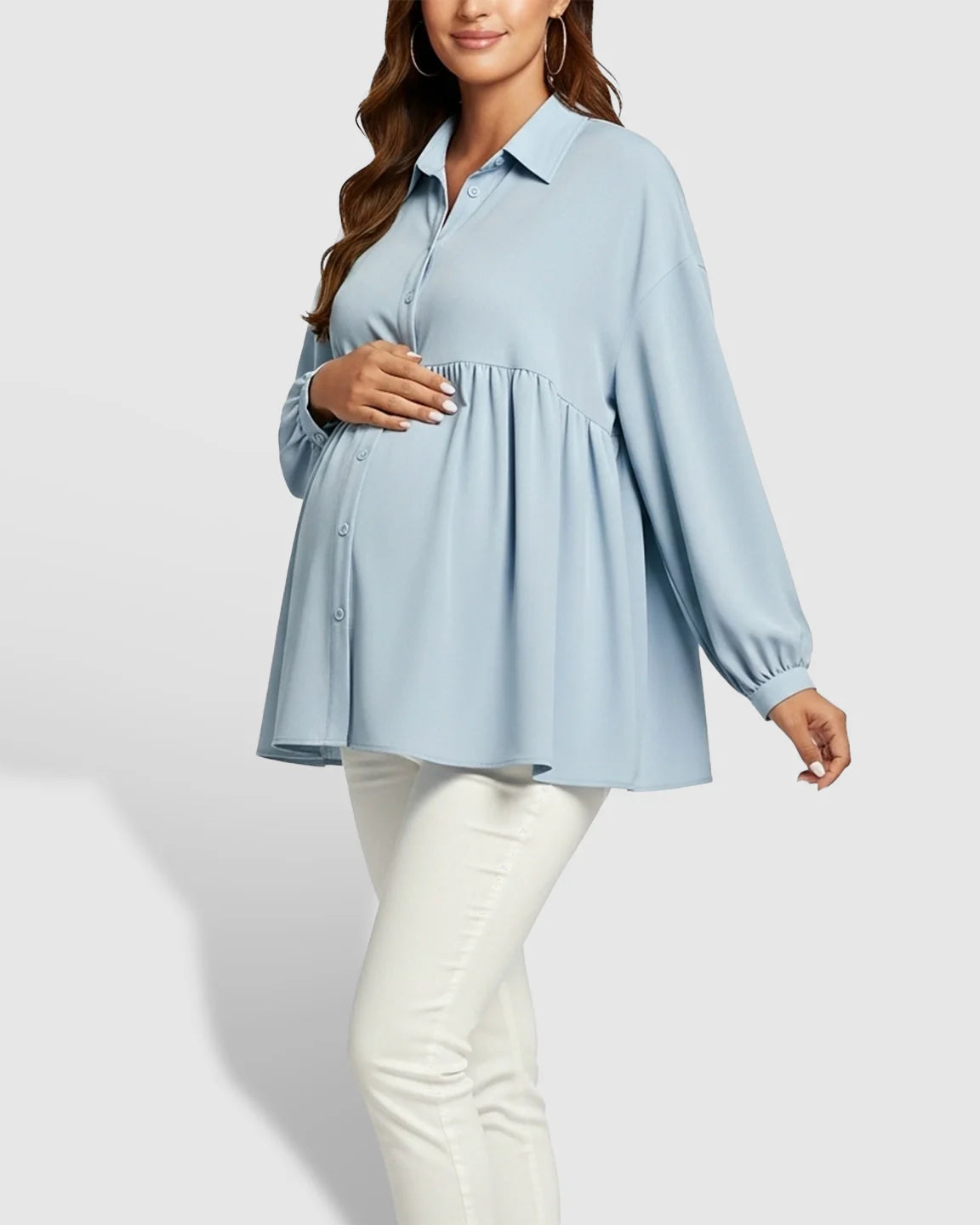 Maternity model in a light blue chiffon babydoll shirt with lapel collar and button-down front, paired with white pants.