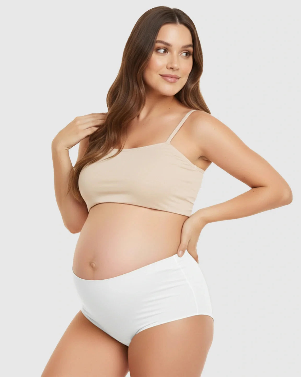 Pregnant woman in a beige seamless maternity bra and white high-waist support underwear.