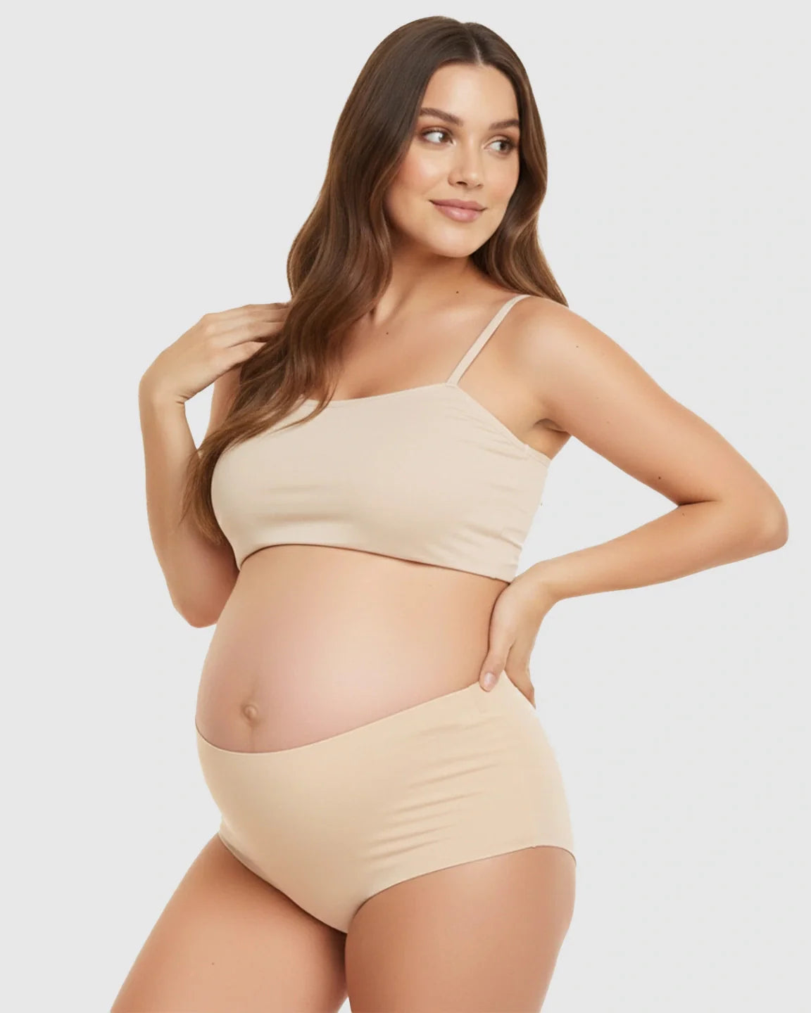 Pregnant woman modeling seamless high-waist nude maternity support underwear and matching crop top.