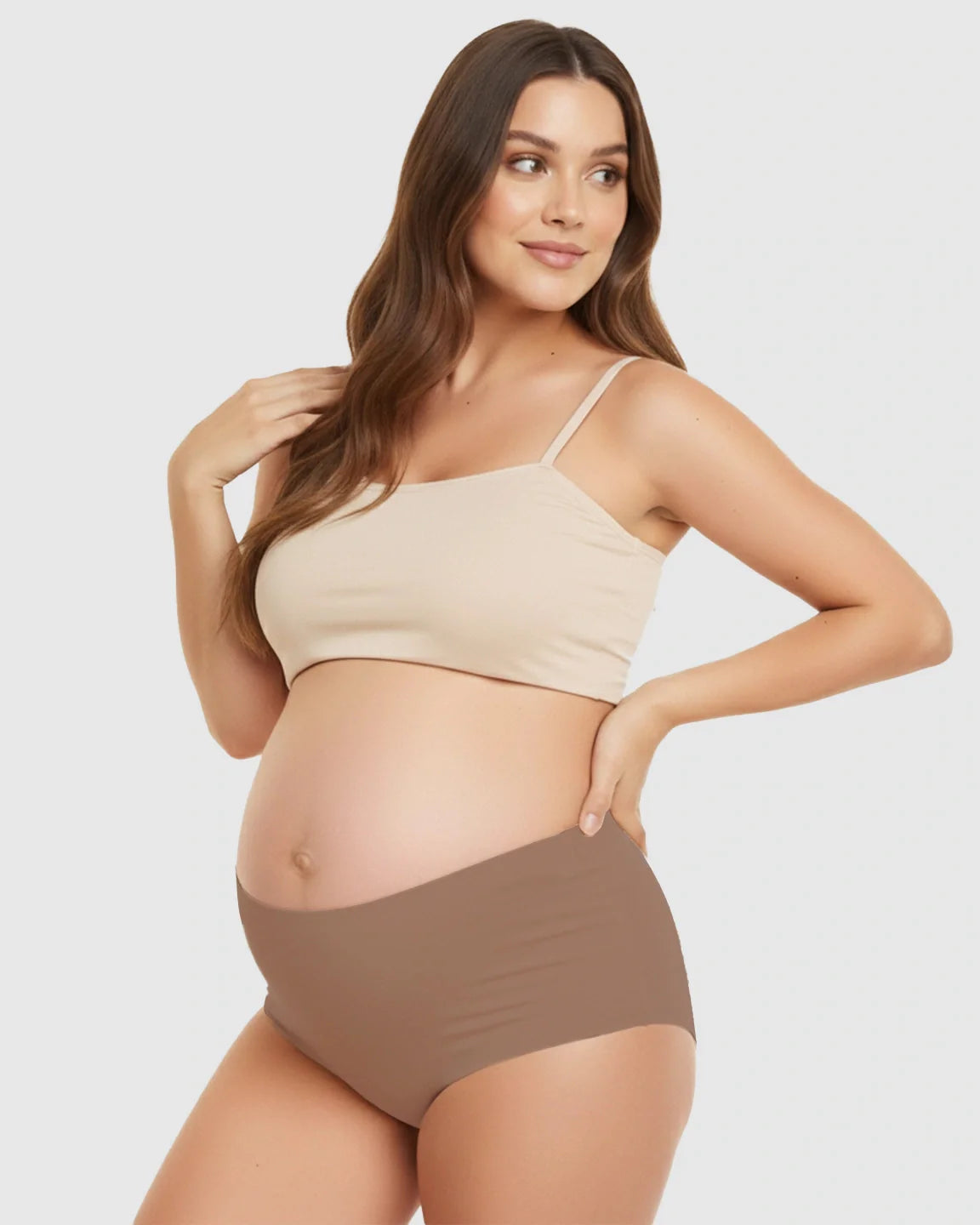 Pregnant woman models seamless high-waist maternity underwear in brown with a matching beige support bra.