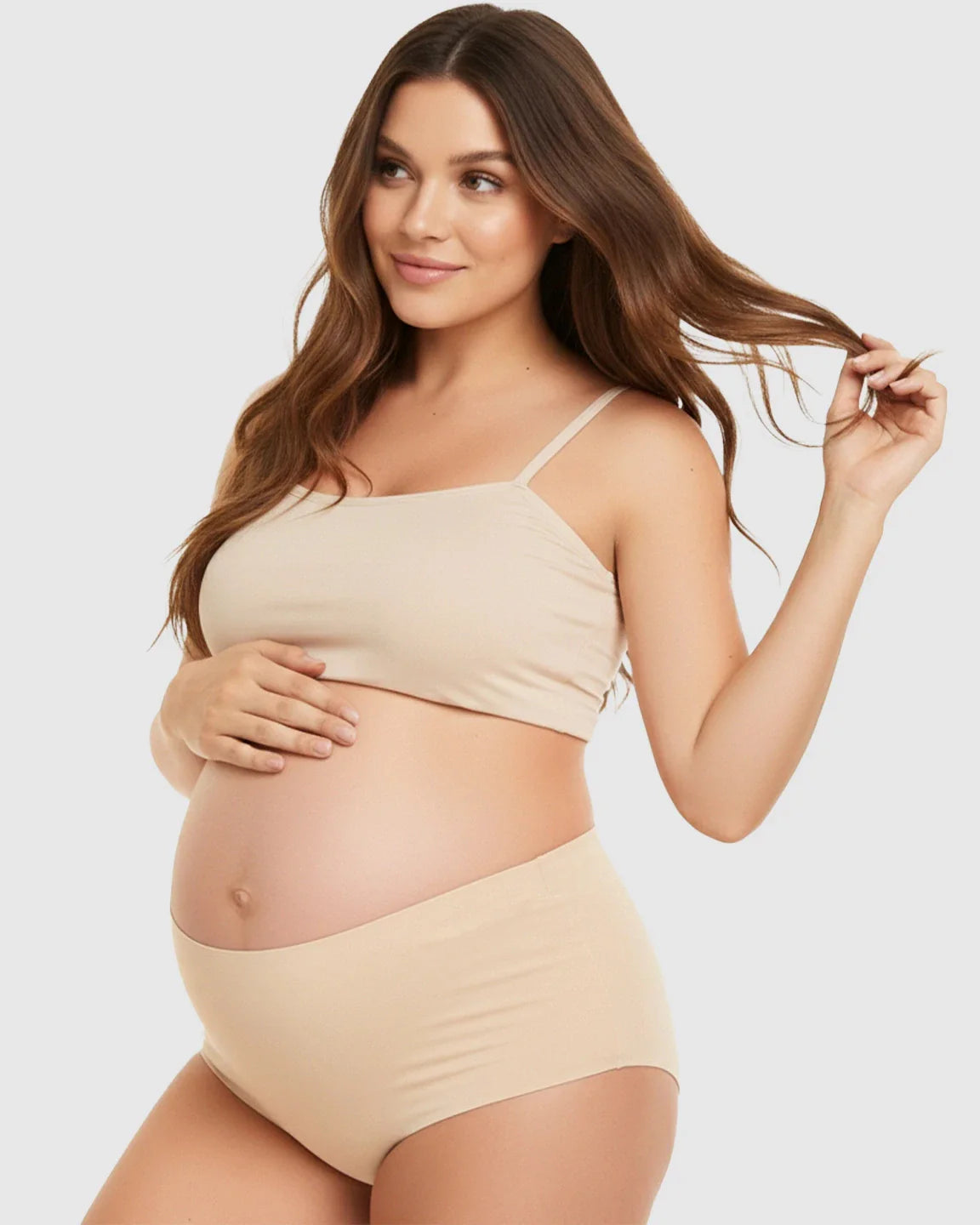 Pregnant woman modeling seamless high-waist support maternity underwear and matching bra in a natural nude color.