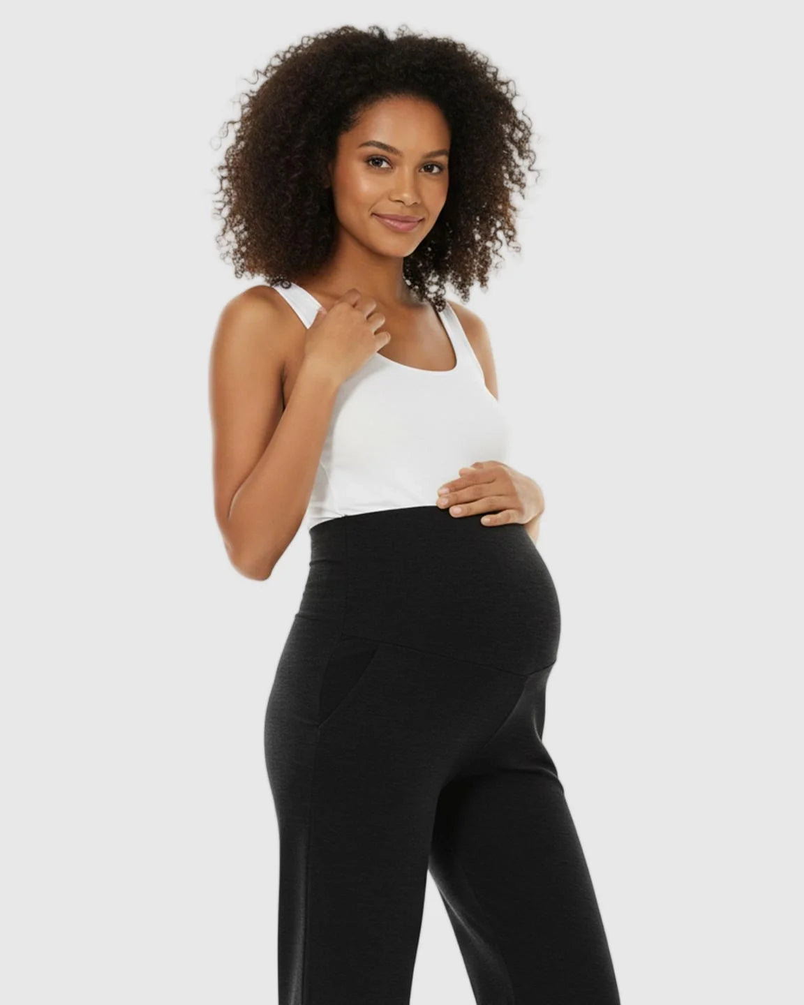Pregnant woman in black wide-leg maternity lounge pants with a foldable waistband and side pockets.